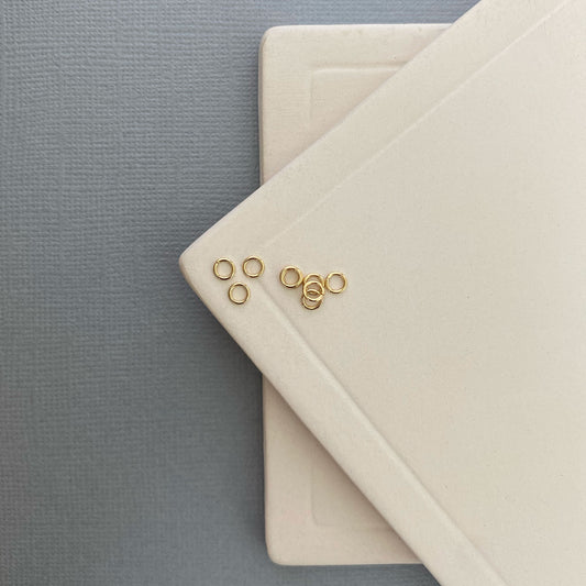 Close-up of a 10K gold jump ring on a flat surface, showcasing its smooth, polished finish and seamless design.