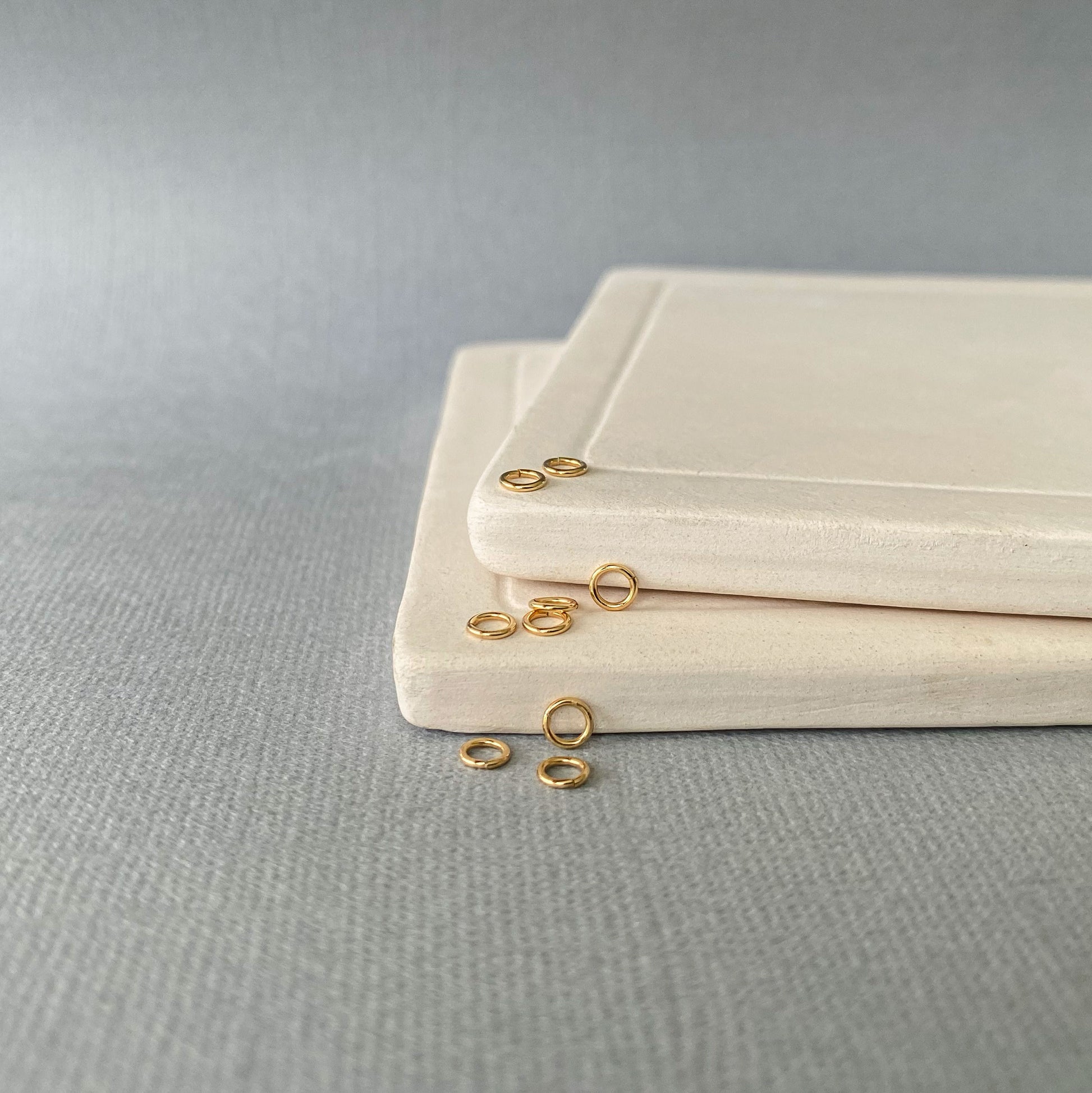 A 10K gold jump ring on a tile with other jump rings.  Showing it's seamless cut.