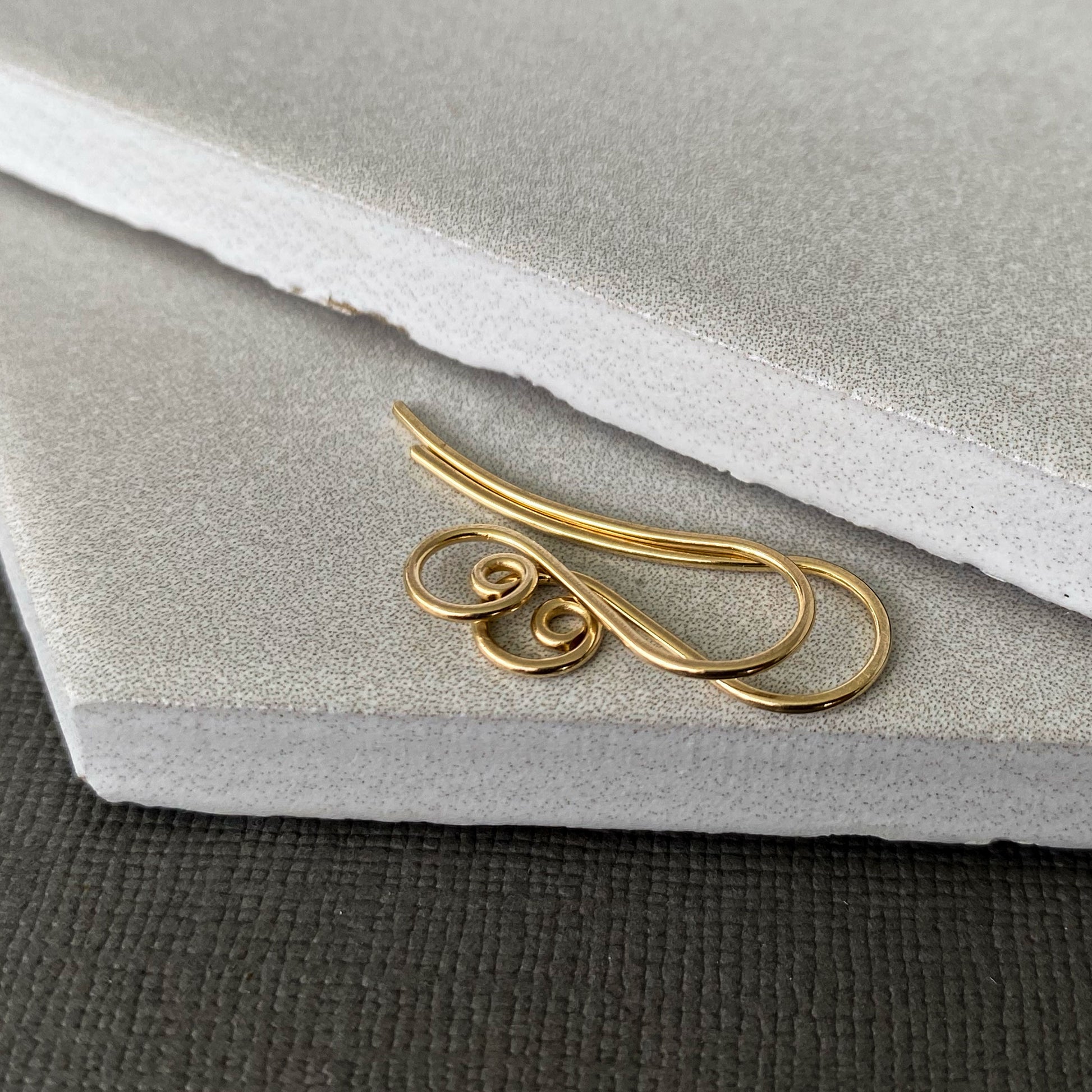 A flat lay of 10K solid gold spiral earring wires on a neutral background, ideal for fine jewelry.