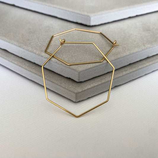 Handcrafted 14k gold-filled heptagon hoop earrings with a polished finish.