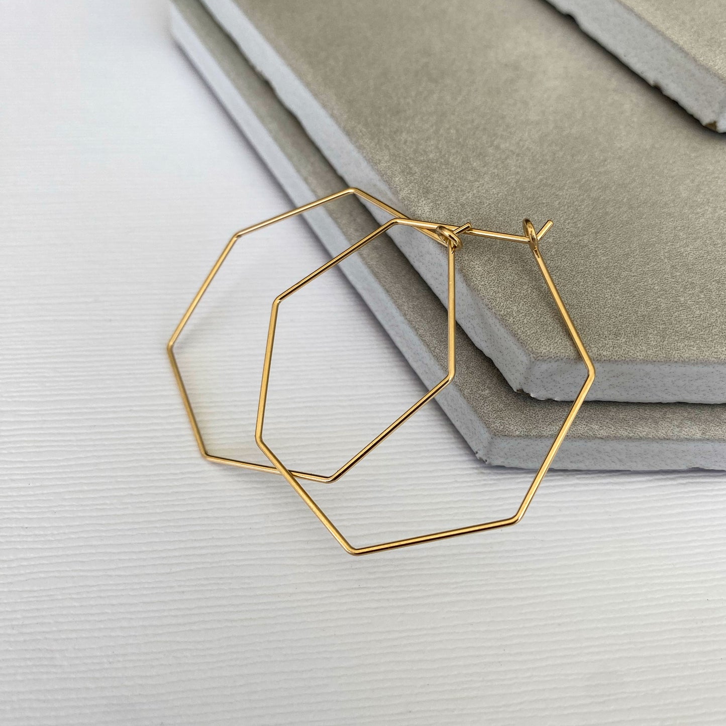 Side view of 14k gold-filled heptagon hoop earrings, showing their thin profile and sleek design.