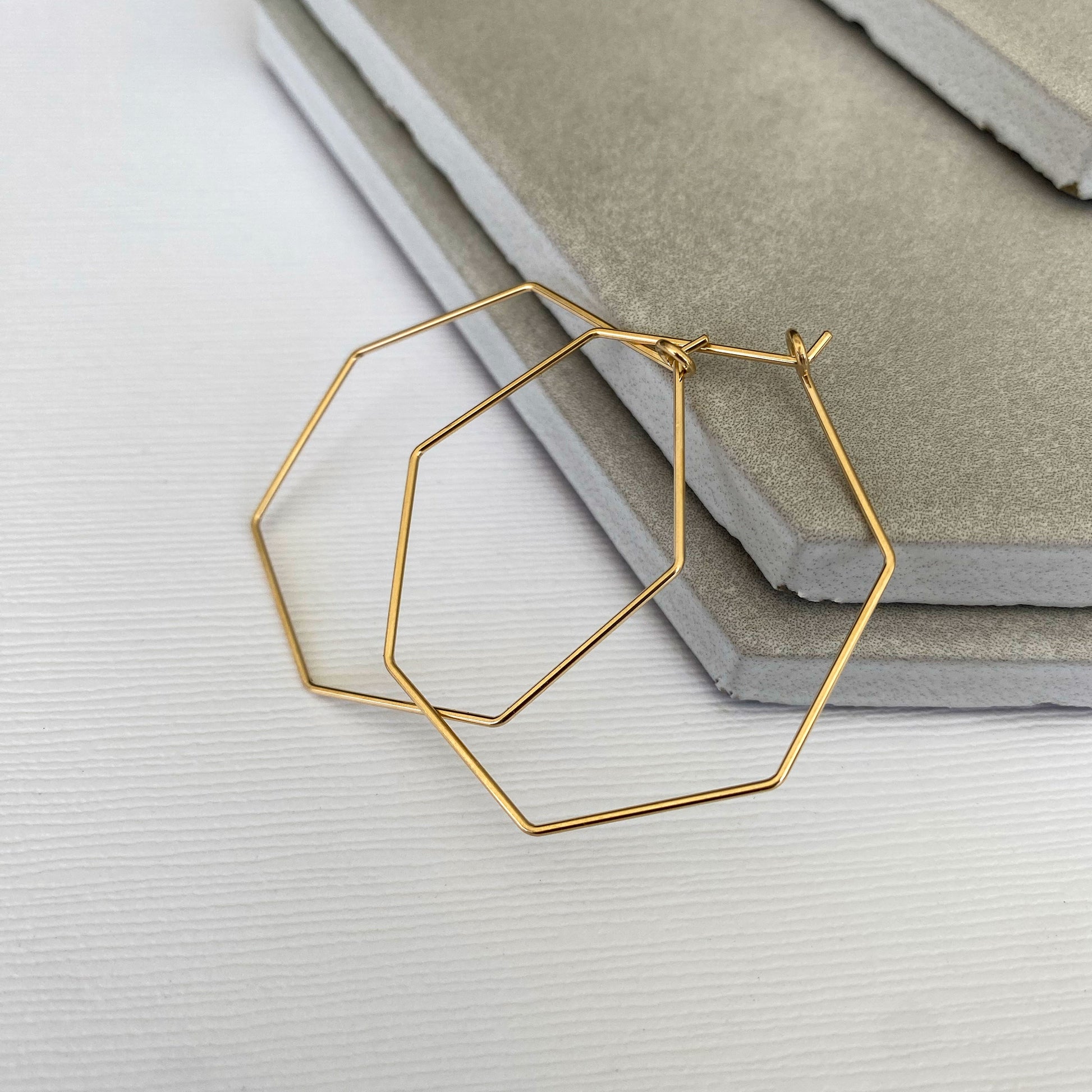 Side view of 14k gold-filled heptagon hoop earrings, showing their thin profile and sleek design.