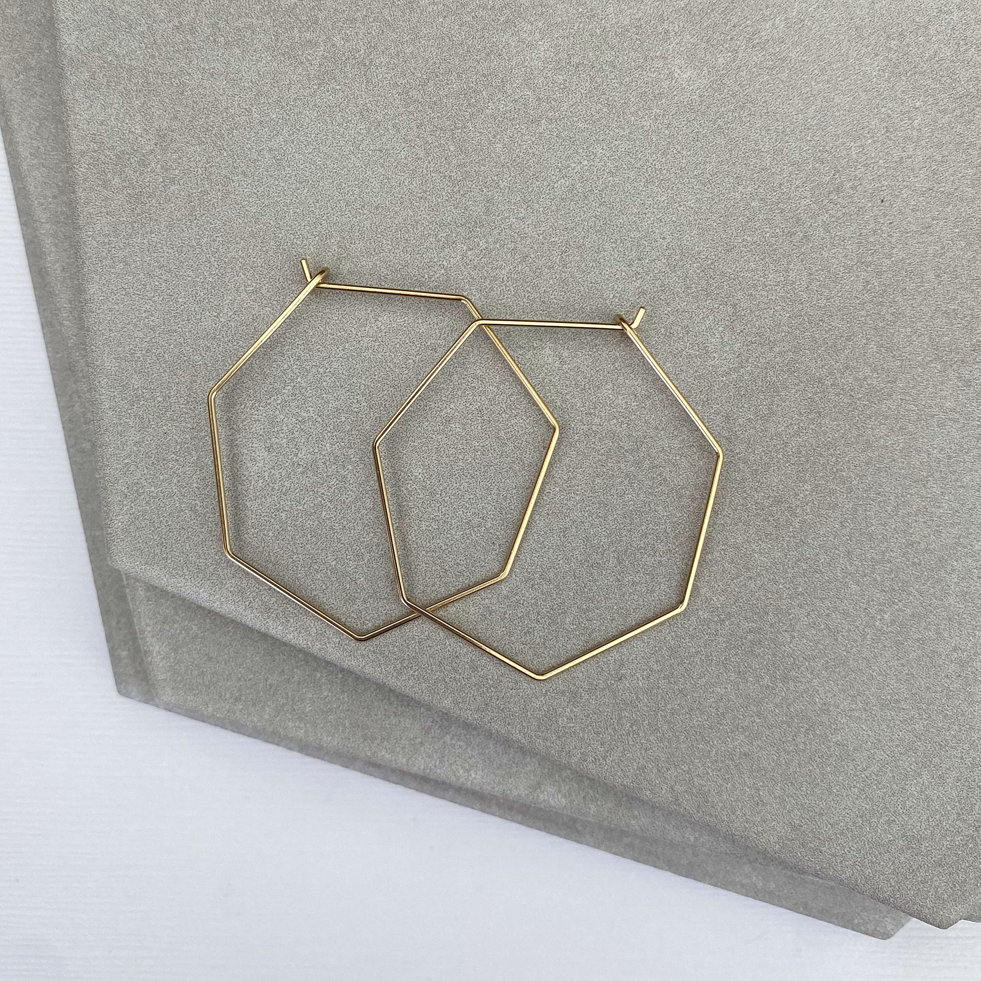 Detailed view of the smooth texture and craftsmanship of 14k gold-filled heptagon hoop earrings.
