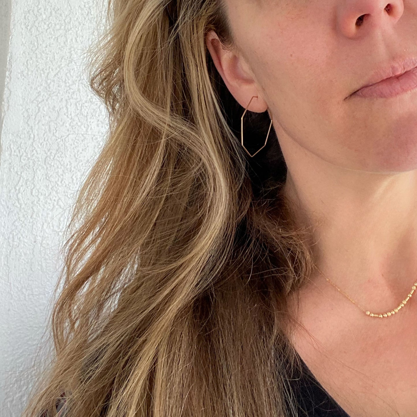 14k gold-filled heptagon hoop earrings worn on a model, showcasing their elegant design.
