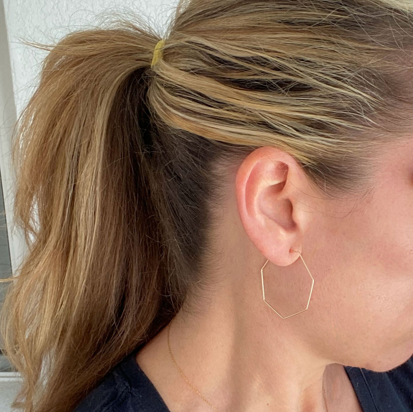 Model wearing 14k gold-filled heptagon hoop earrings, highlighting their stylish geometric shape.