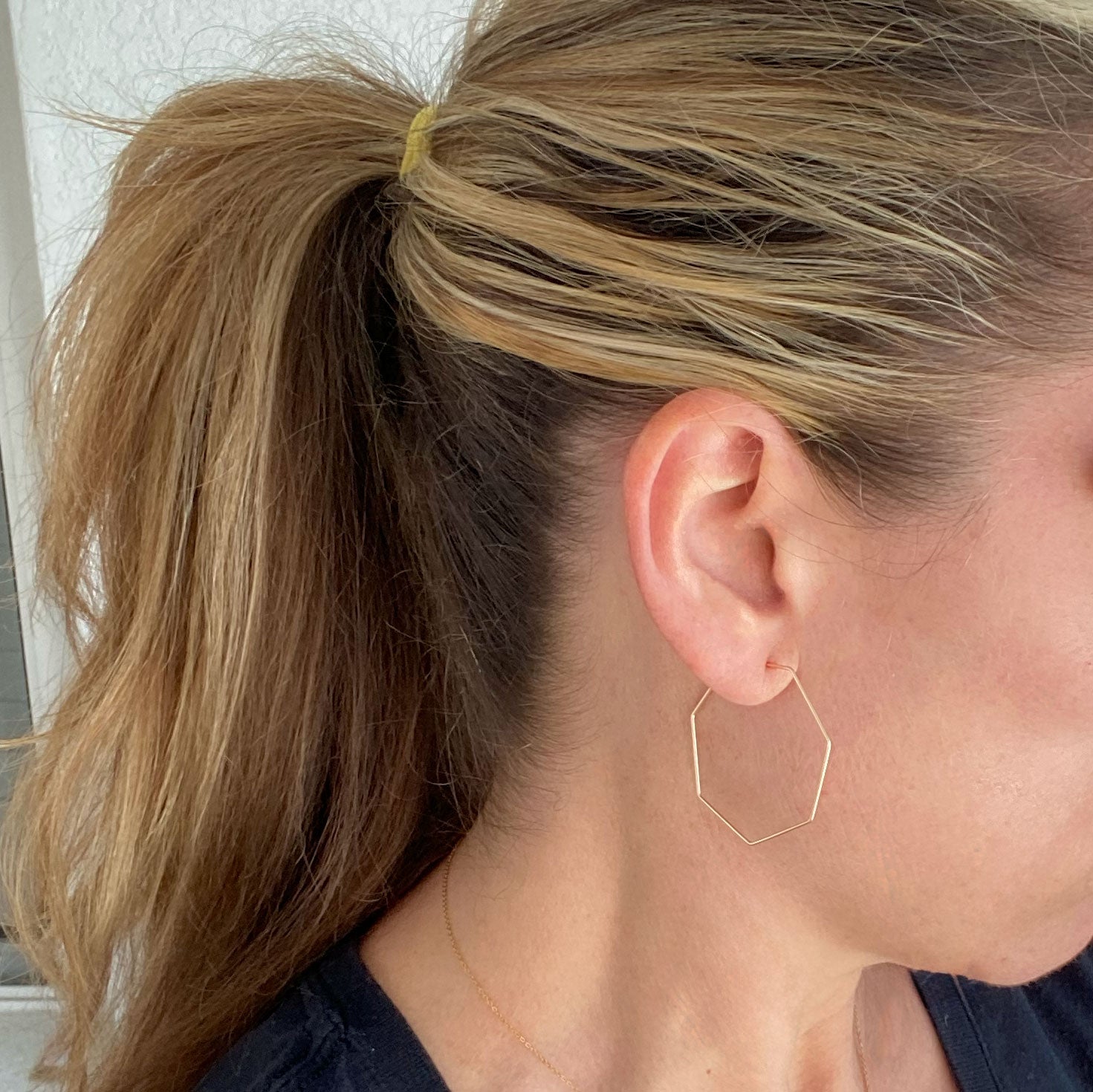 Model wearing 14k gold-filled heptagon hoop earrings, highlighting their stylish geometric shape.