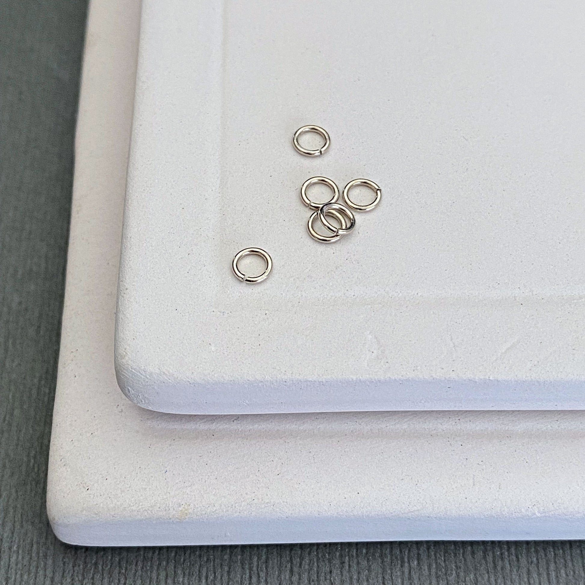 A group of 14k white gold palladium jump rings, 2.5mm, neatly arranged to showcase their uniformity and smooth finish.