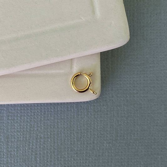 Close-up of a 14k yellow gold spring ring clasp with an open ring for easy jewelry assembly