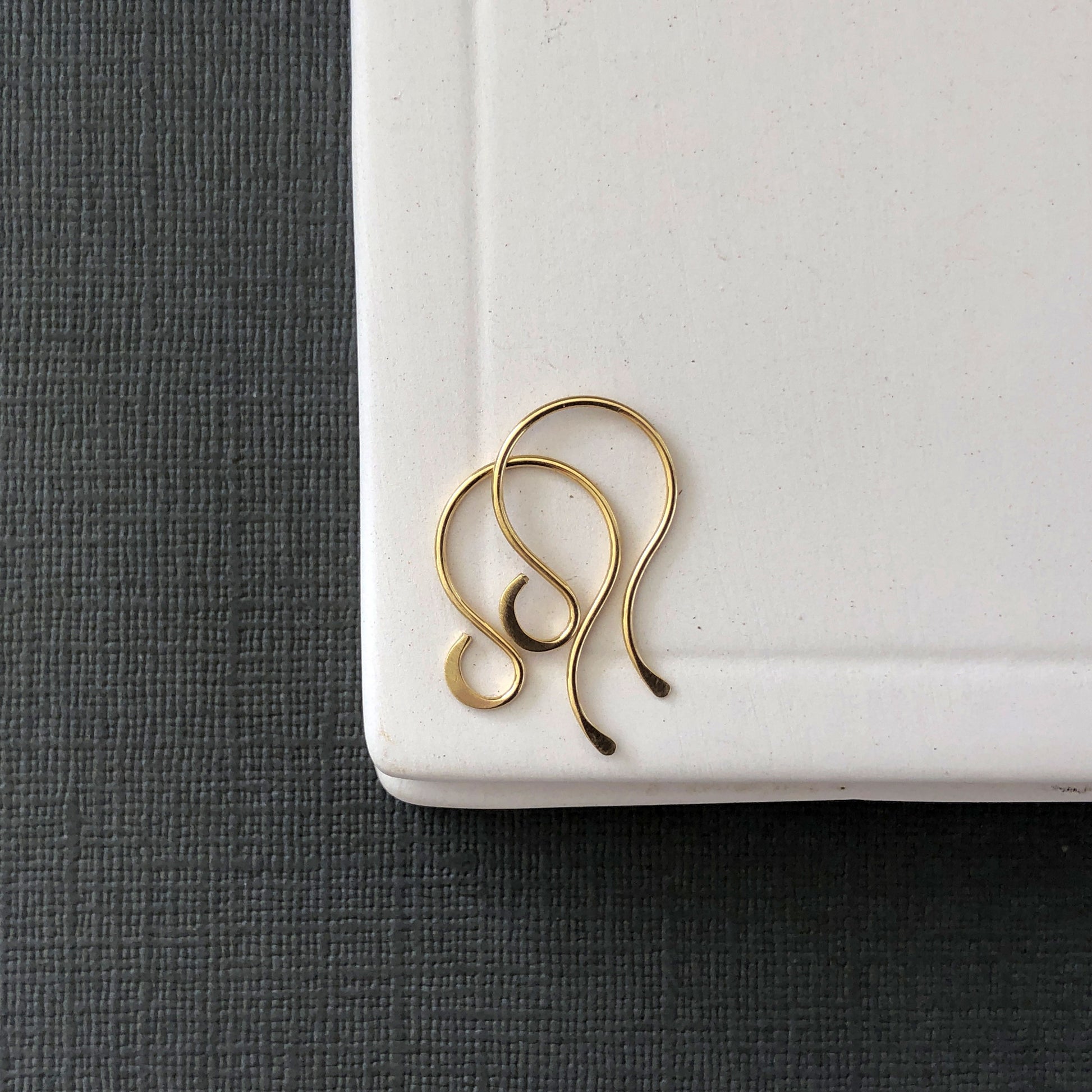 Side angle of 18k gold earring wires showing curved shape