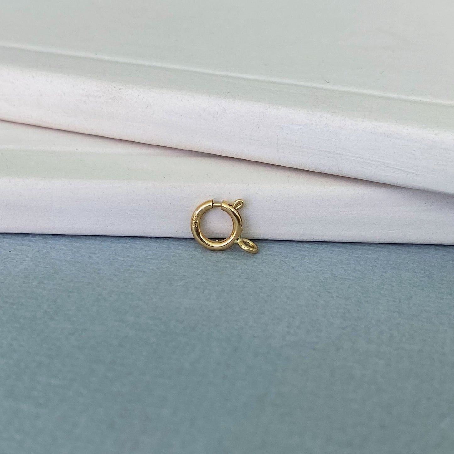 Detailed view of an Italian-made 14k gold spring ring clasp with a 585 hallmark