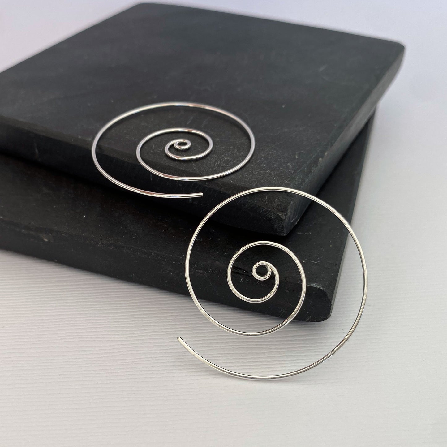 Large spiral hoop earrings. Handmade, using solid sterling silver wire. Lightly hammered flat.