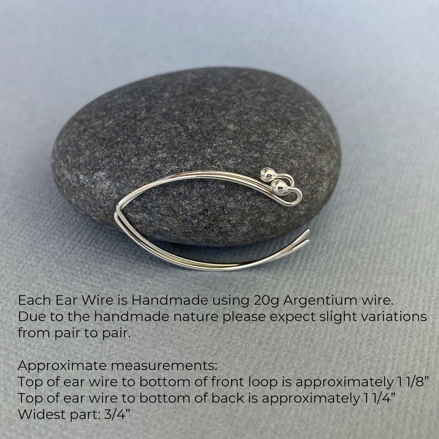 A pair of 20-gauge Argentium silver ear wires displayed with a rock to show their approximate size.
