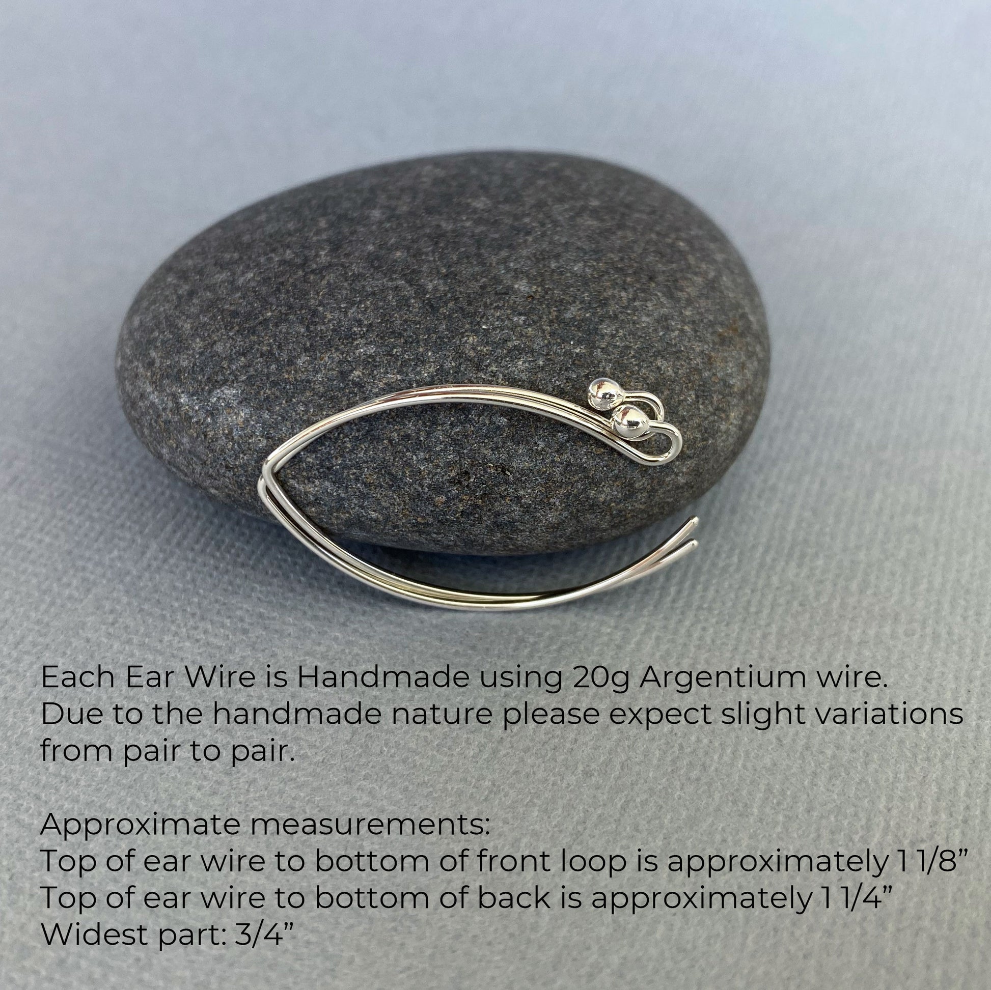 A pair of 20-gauge Argentium silver ear wires displayed with a rock to show their approximate size.