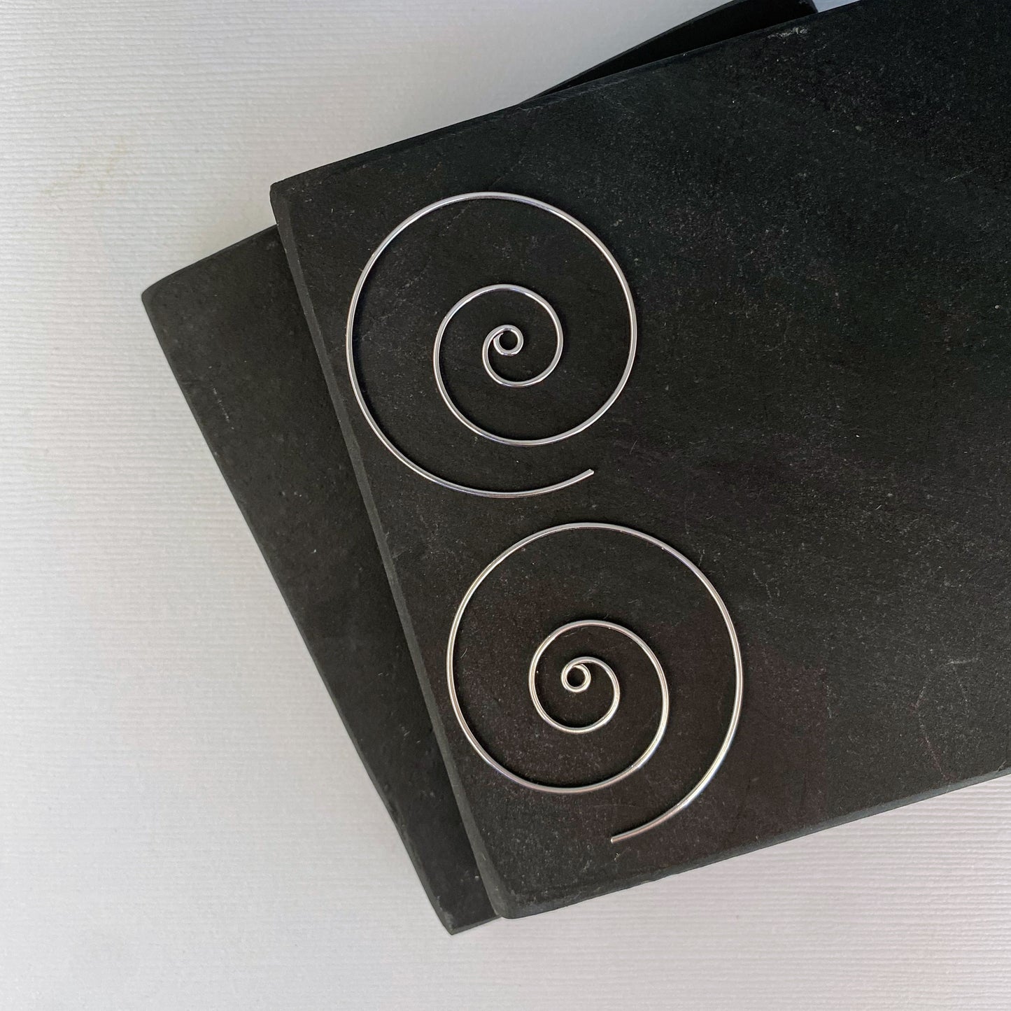 Large spiral hoop earrings. Handmade, using solid sterling silver wire. Lightly hammered flat.