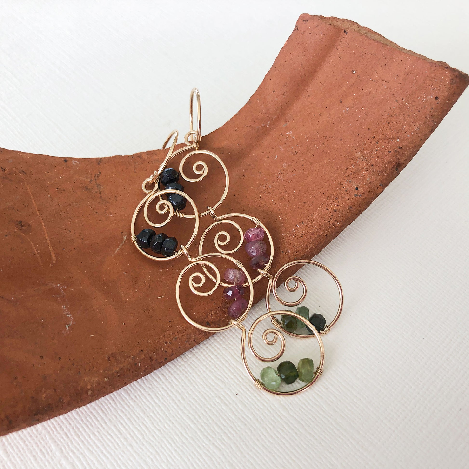Full view of tourmaline dangle earrings – Elegant 14K gold-filled earrings with handcrafted spiral hoops and colorful tourmaline gemstones, displayed against a neutral background.