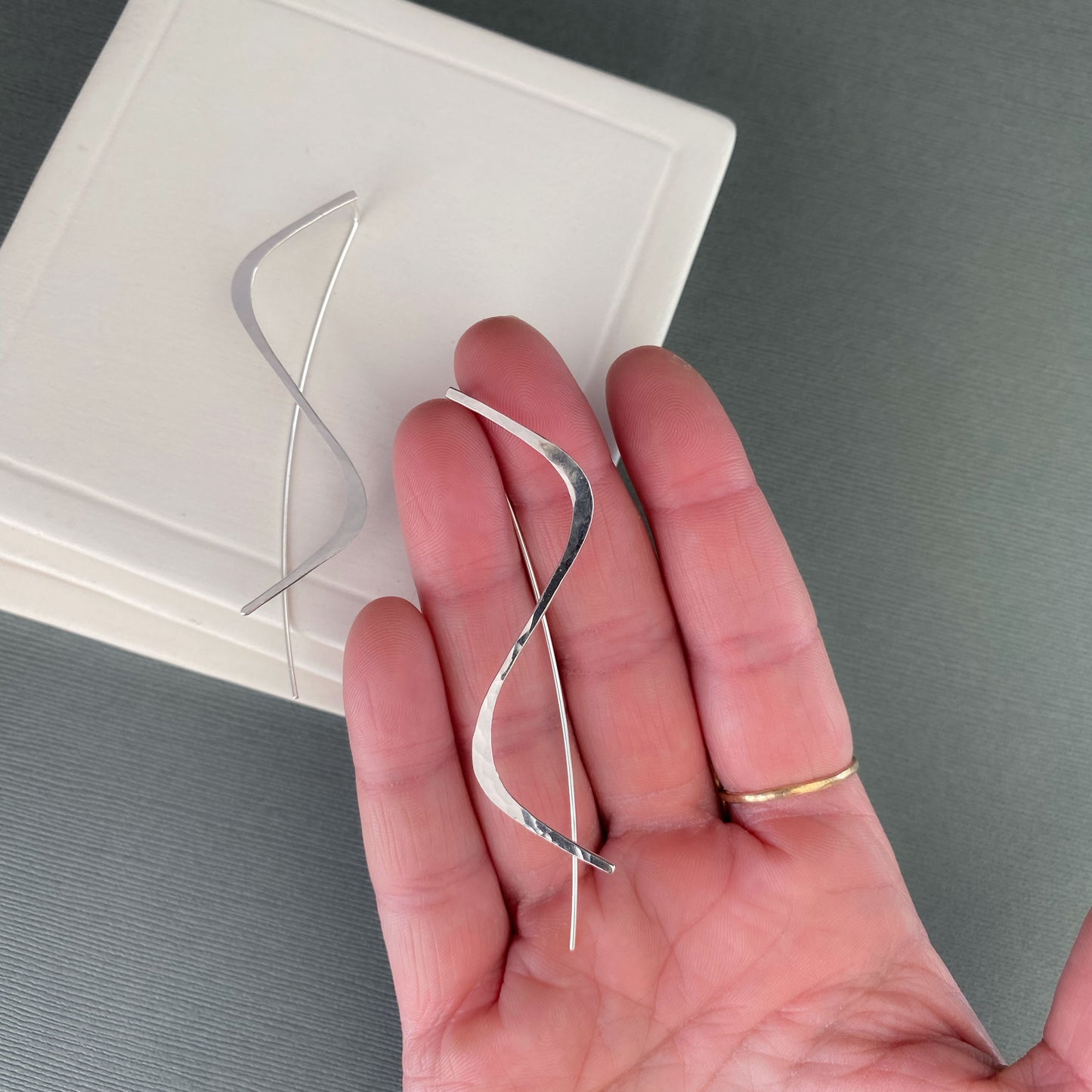 sterling silver handmade threader earrings being held in a hand.