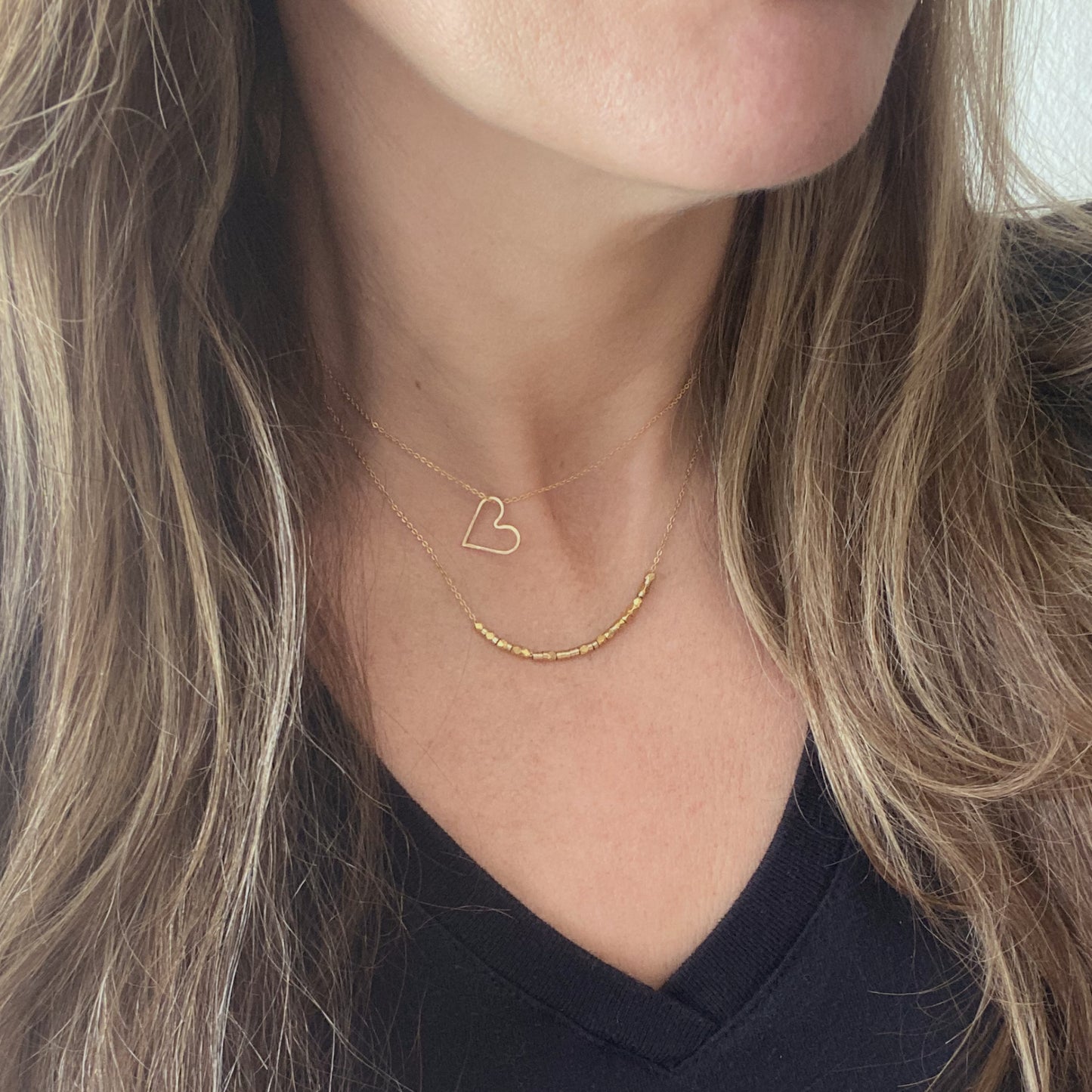 A model wearing a 14k gold filled custom-length chain layered with another necklace to show a stylish stacking look.