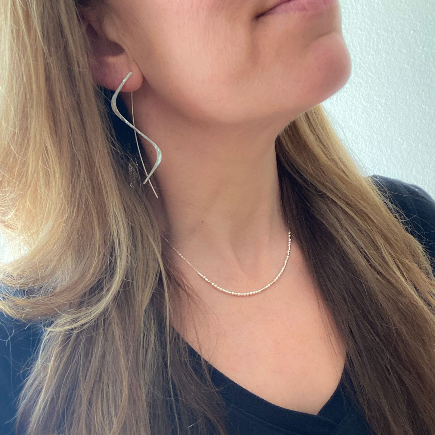 A model wearing the long sterling silver threader earrings to show their 2.5-inch length and fit.