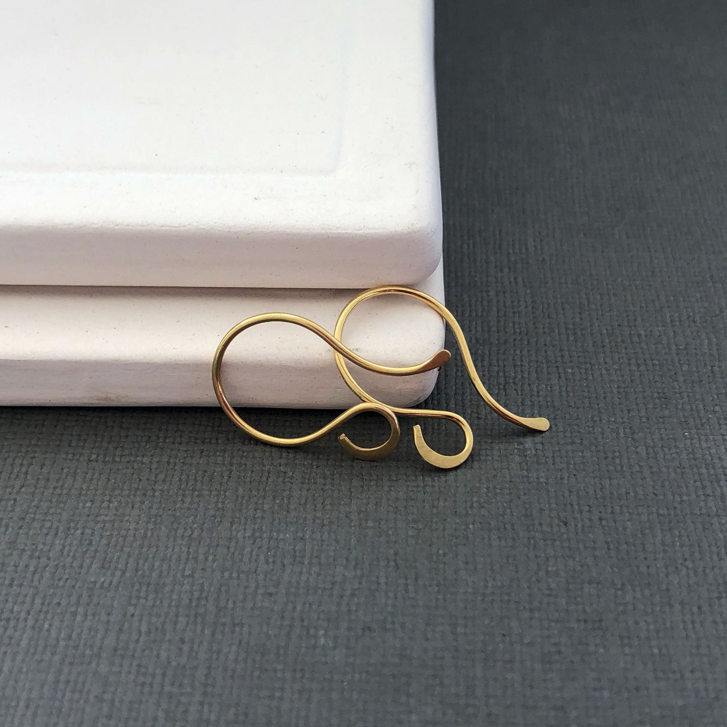Pair of 18k gold French hooks displayed flat on surface