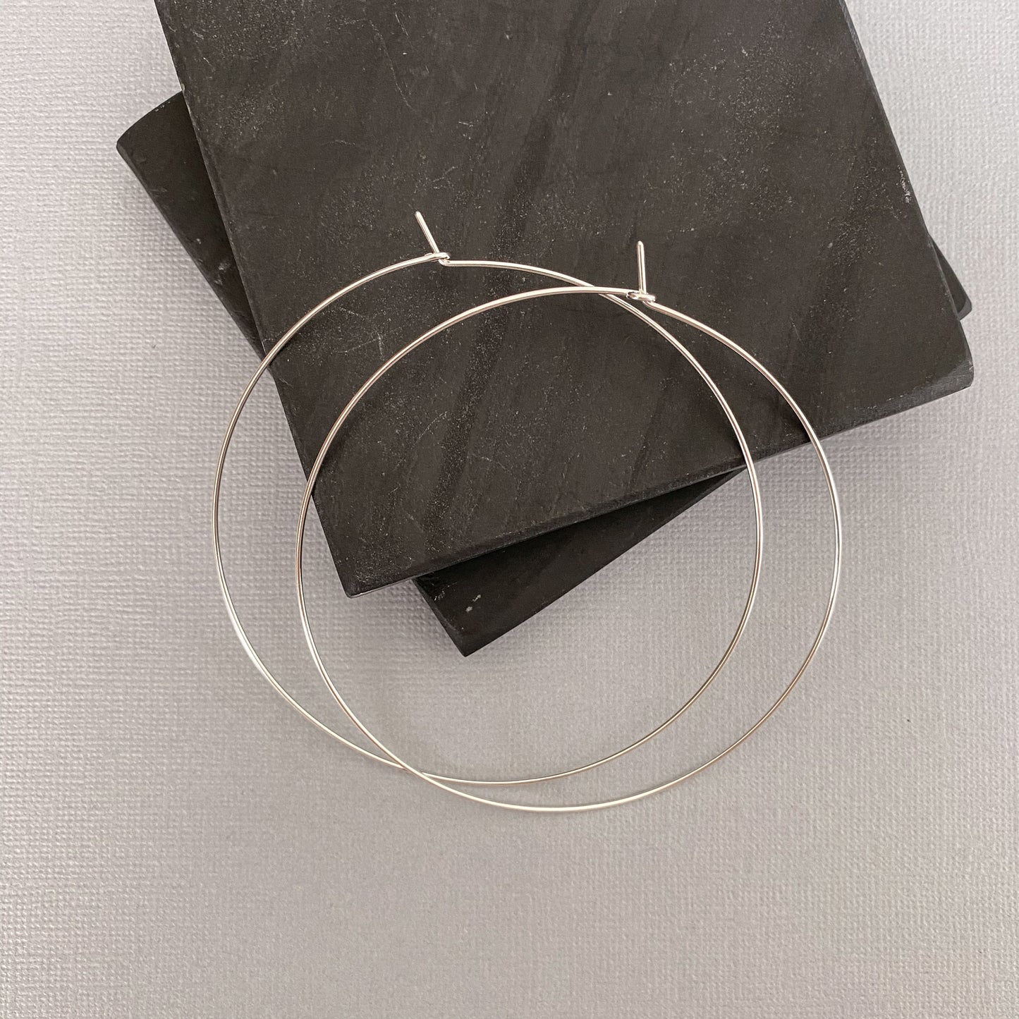 Side view of sterling silver hoop earrings, showcasing their thin yet sturdy construction.