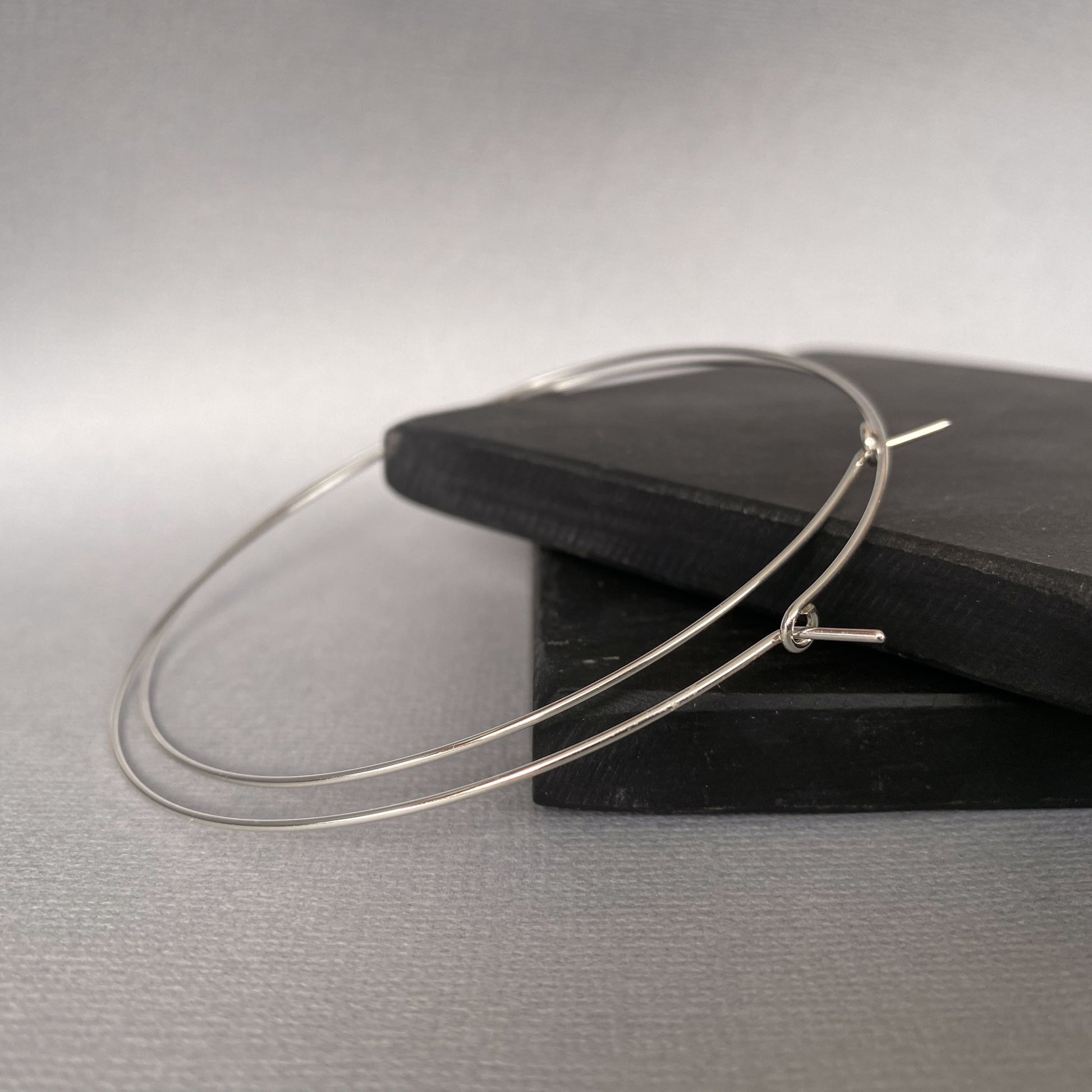 A pair of 2-inch sterling silver hoop earrings, featuring a smooth, polished finish for a classic everyday look.