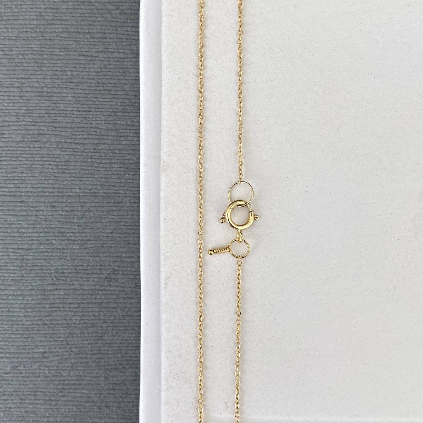 A thin 14k gold filled stacking chain coiled to show its fluidity and the rich color of its 18k gold plating.