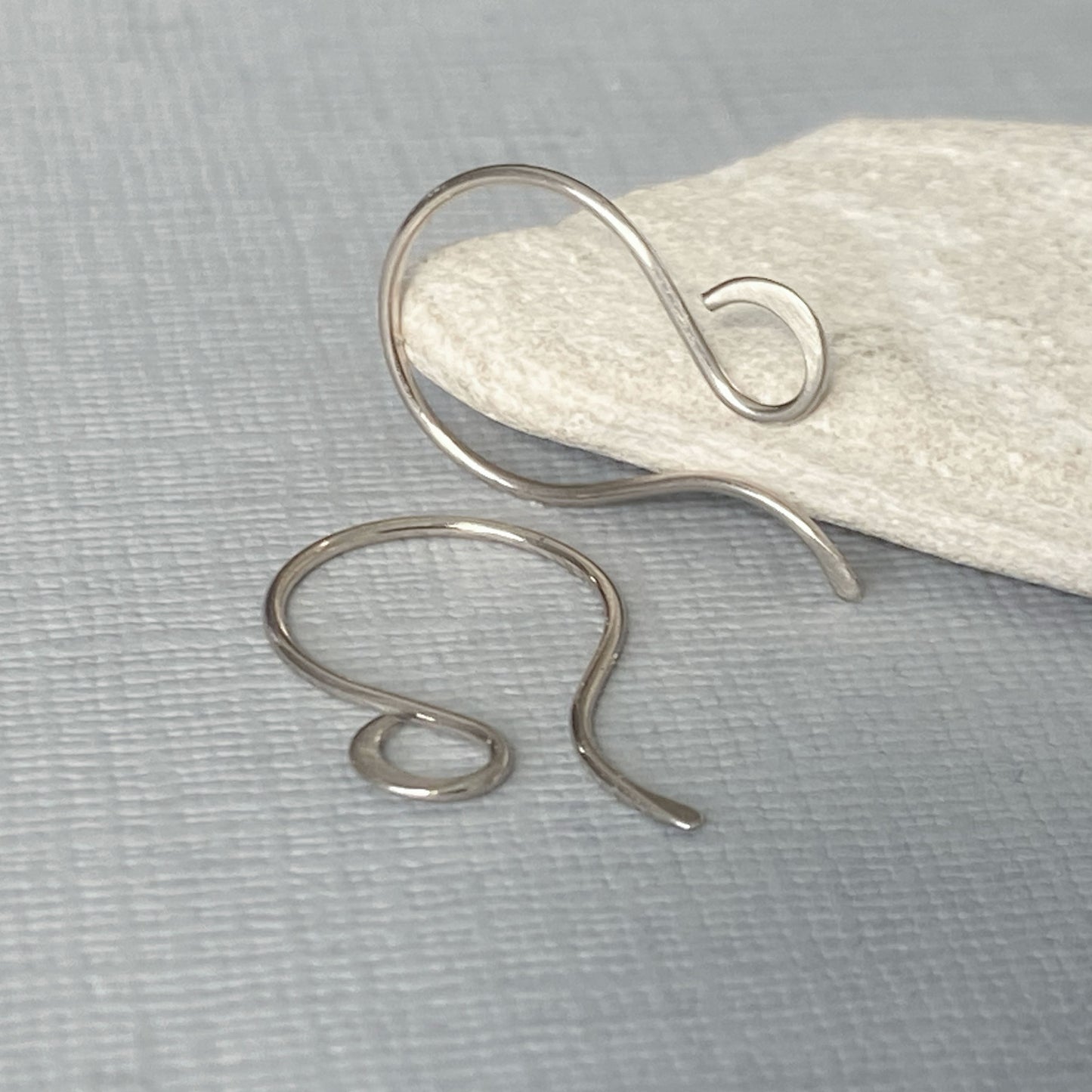 14K white gold ear wires leaning on rock to show scale and size.