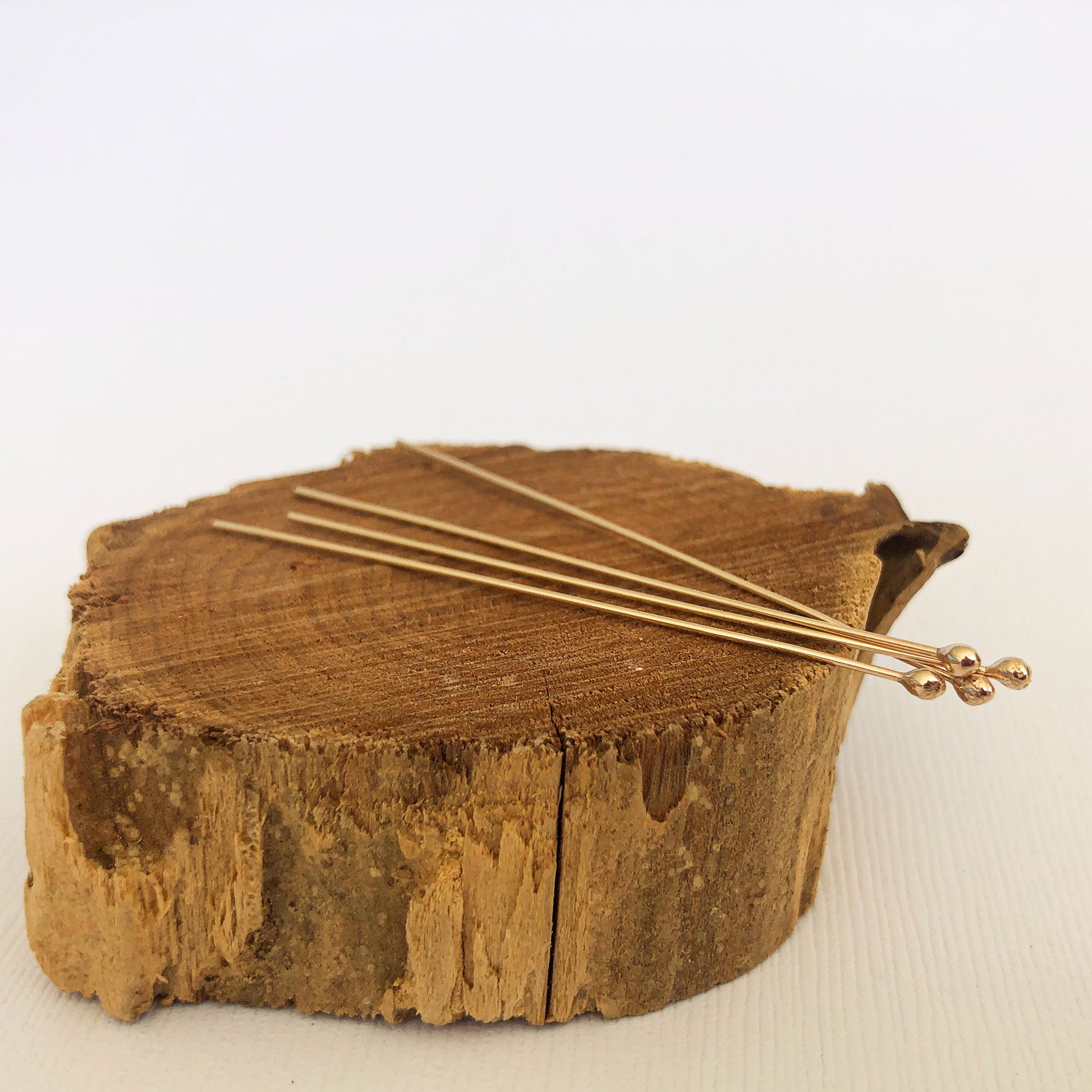 side photo of 4 gold ball headpins displayed on a brown peice of wood.  Use this to  ake jewelry