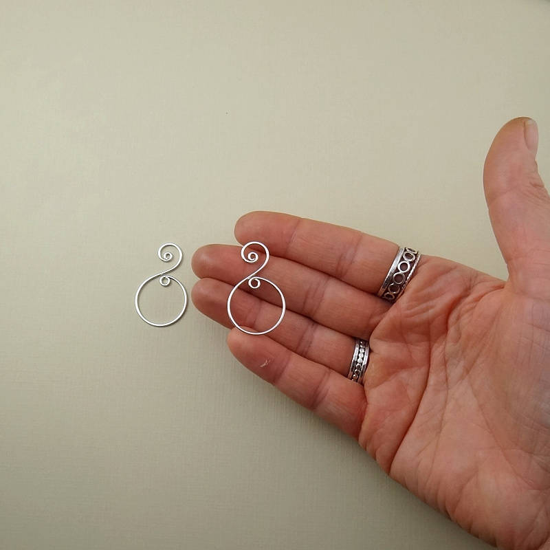 Sterling silver spiral drop charm displayed on a neutral background, highlighting its handcrafted details.