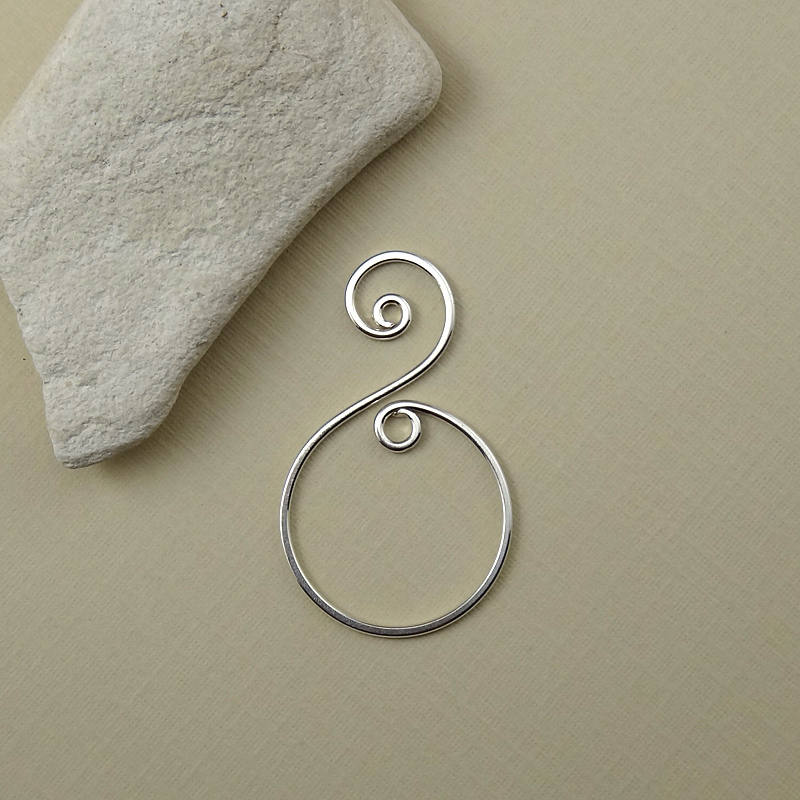 Close-up of a handmade sterling silver spiral drop charm, shaped from 18 gauge .925 silver and hammered for strength.