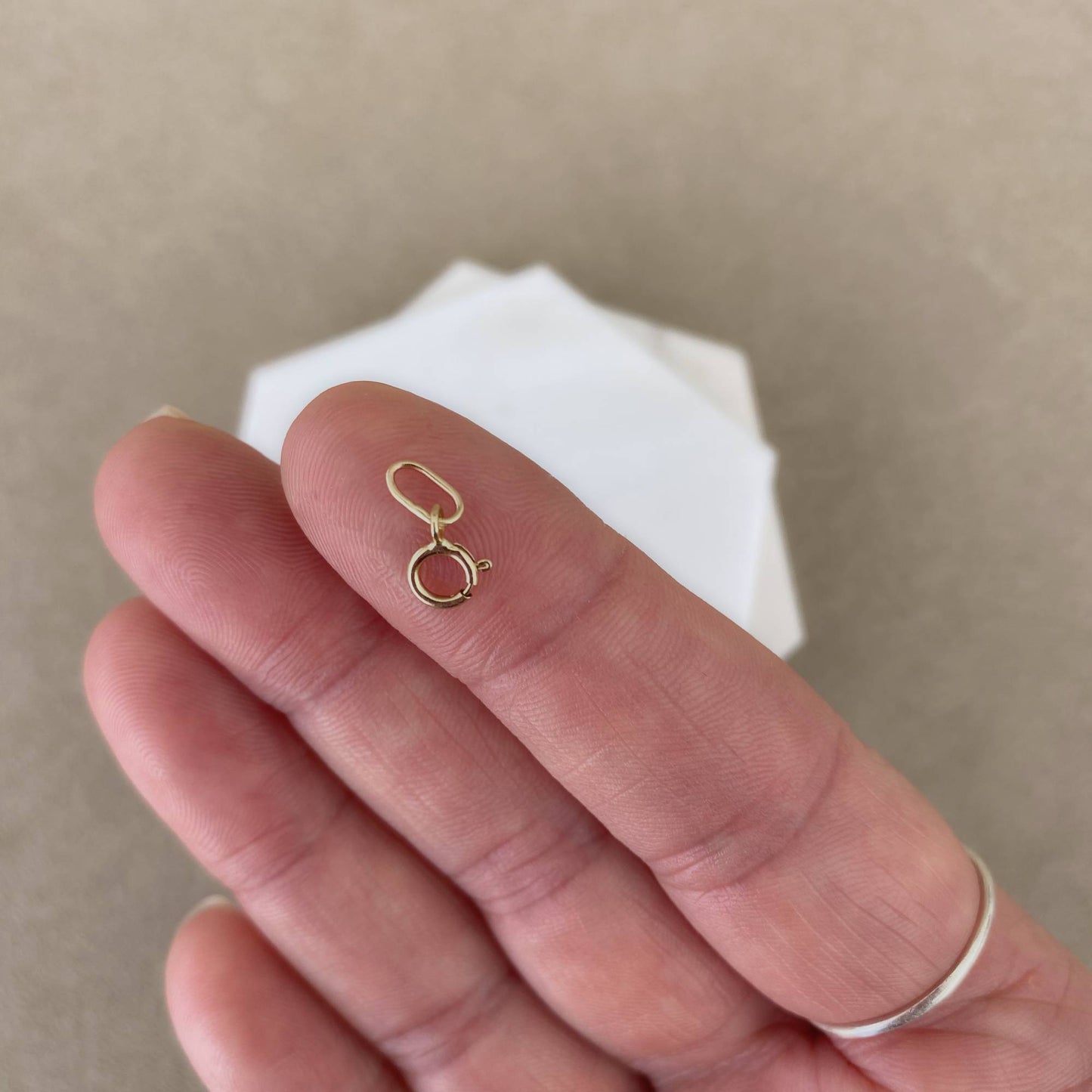 14k solid gold charm extender shown on fingertip to illustrate small dainty size