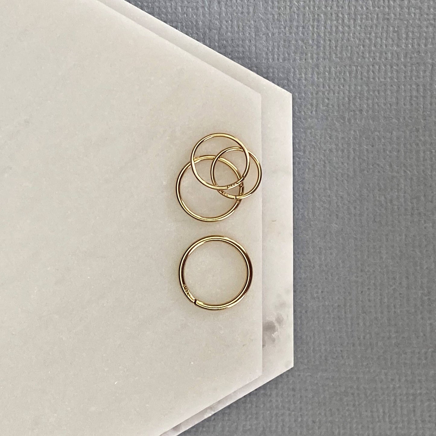 Macro shot of the 14k hallmark stamp on the inside of a solid gold nose ring for authenticity.