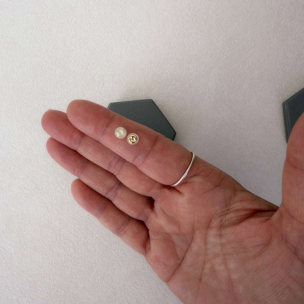 14K solid gold silicone earring backs shown on a hand for size reference