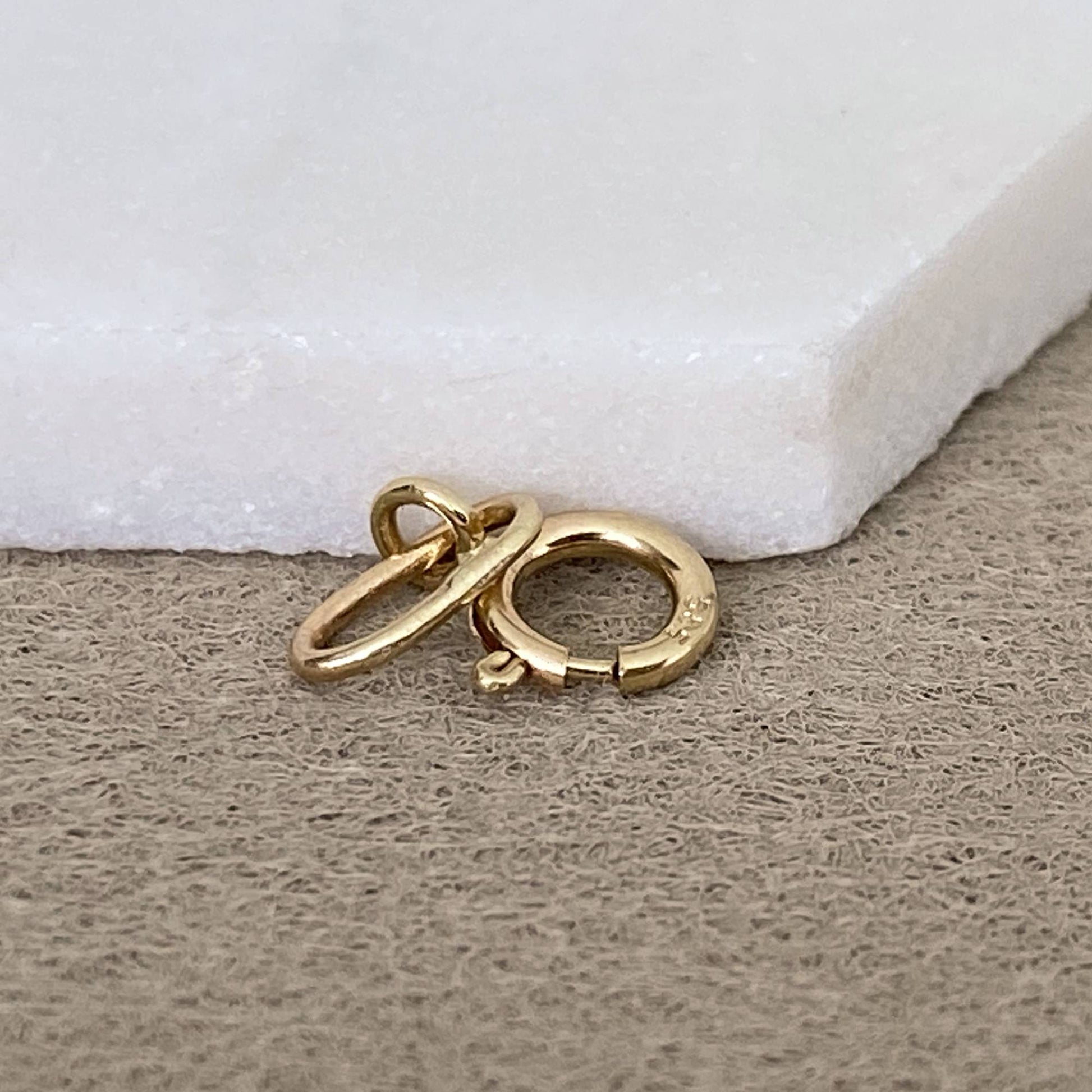 14k solid gold charm holder with spring ring clasp on marble tray