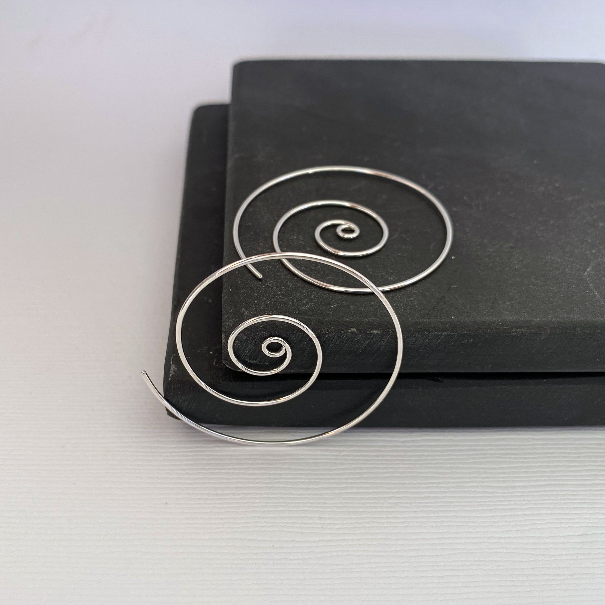 Large spiral hoop earrings.  Handmade, using solid sterling silver wire. Lightly hammered flat.