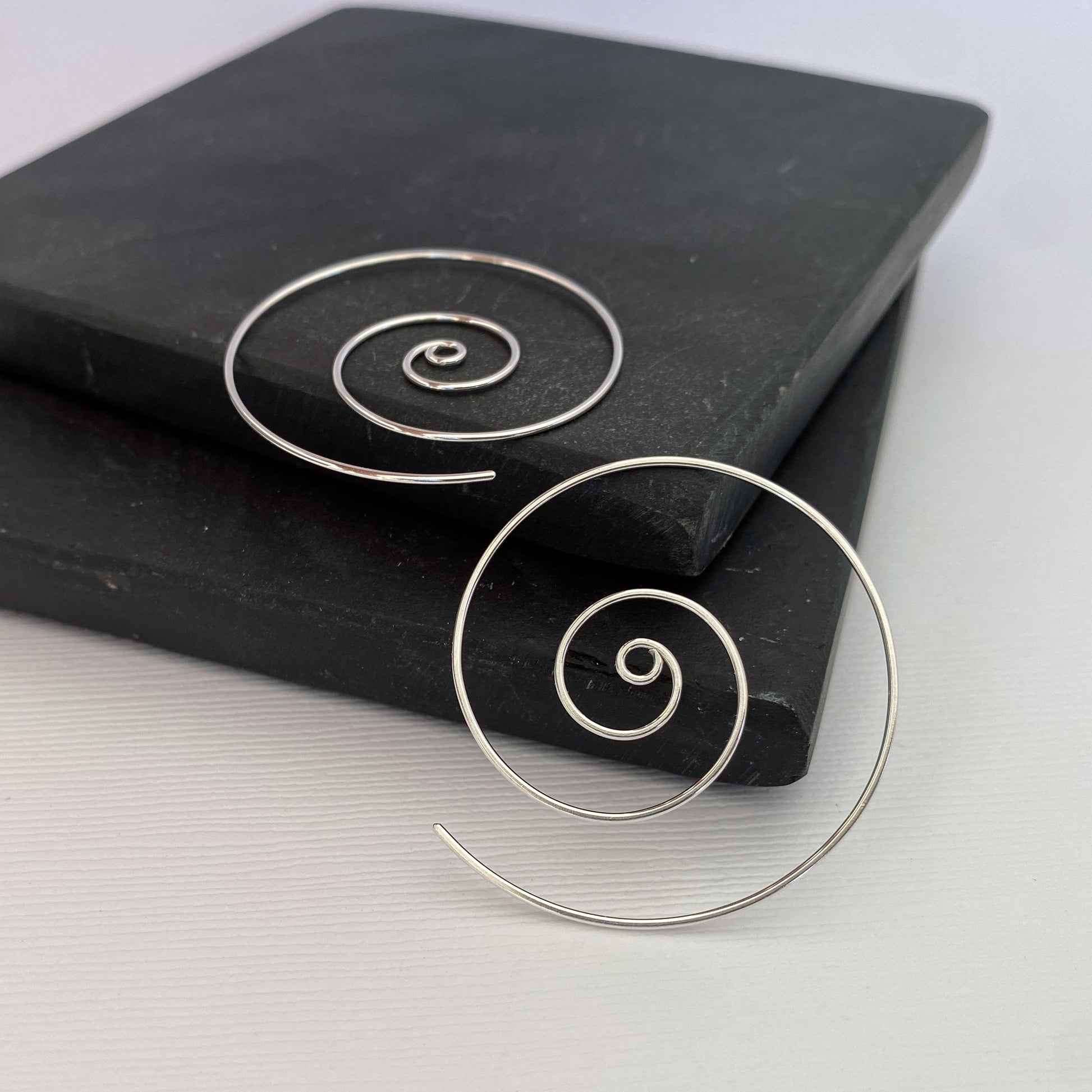 Large spiral hoop earrings.  Handmade, using solid sterling silver wire. Lightly hammered flat.