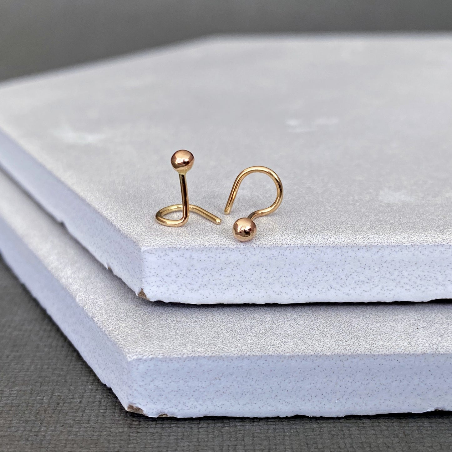 Gold earrings on a textured white surface