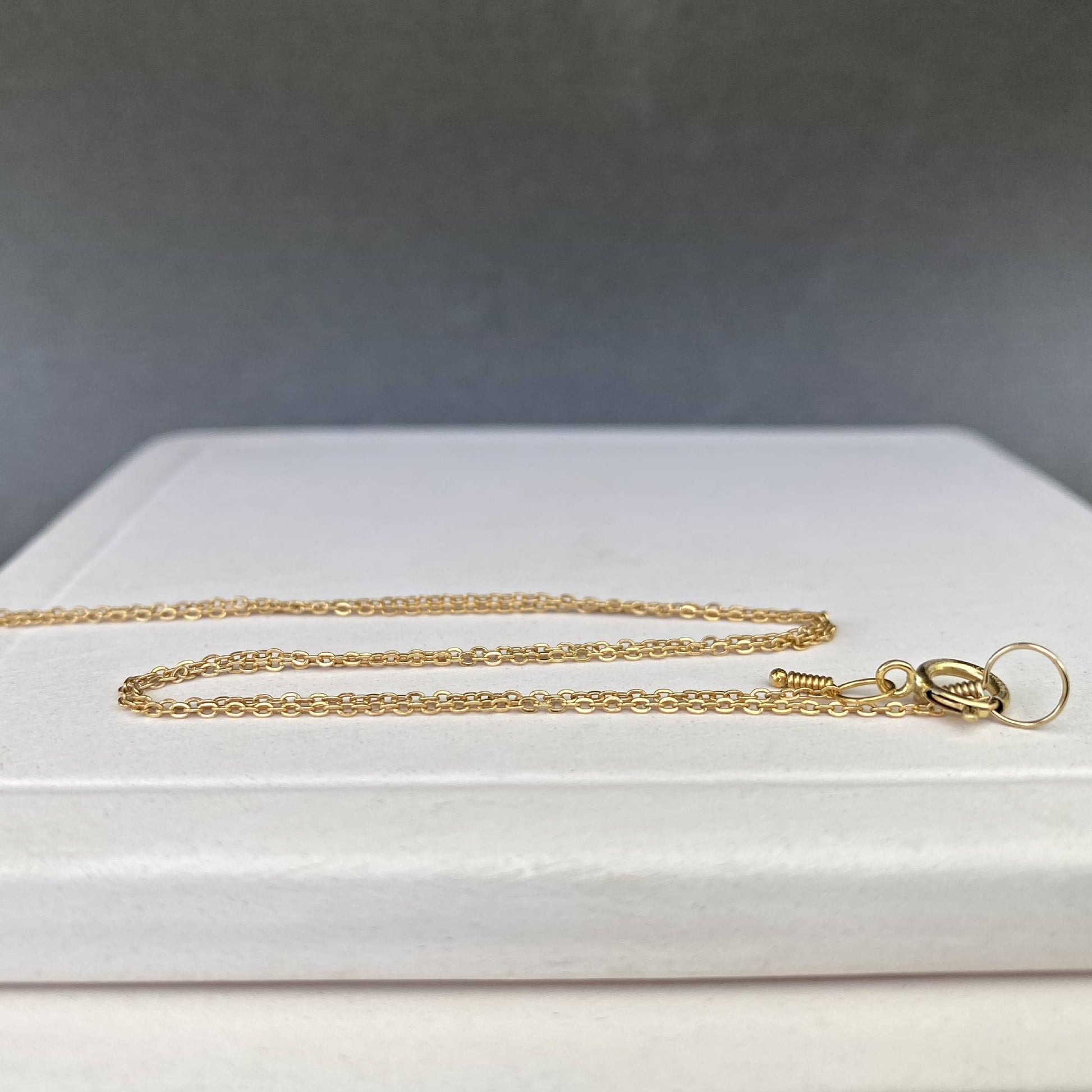 Two 14k gold filled custom-length chains laid side-by-side to show their versatility for a stacking look.