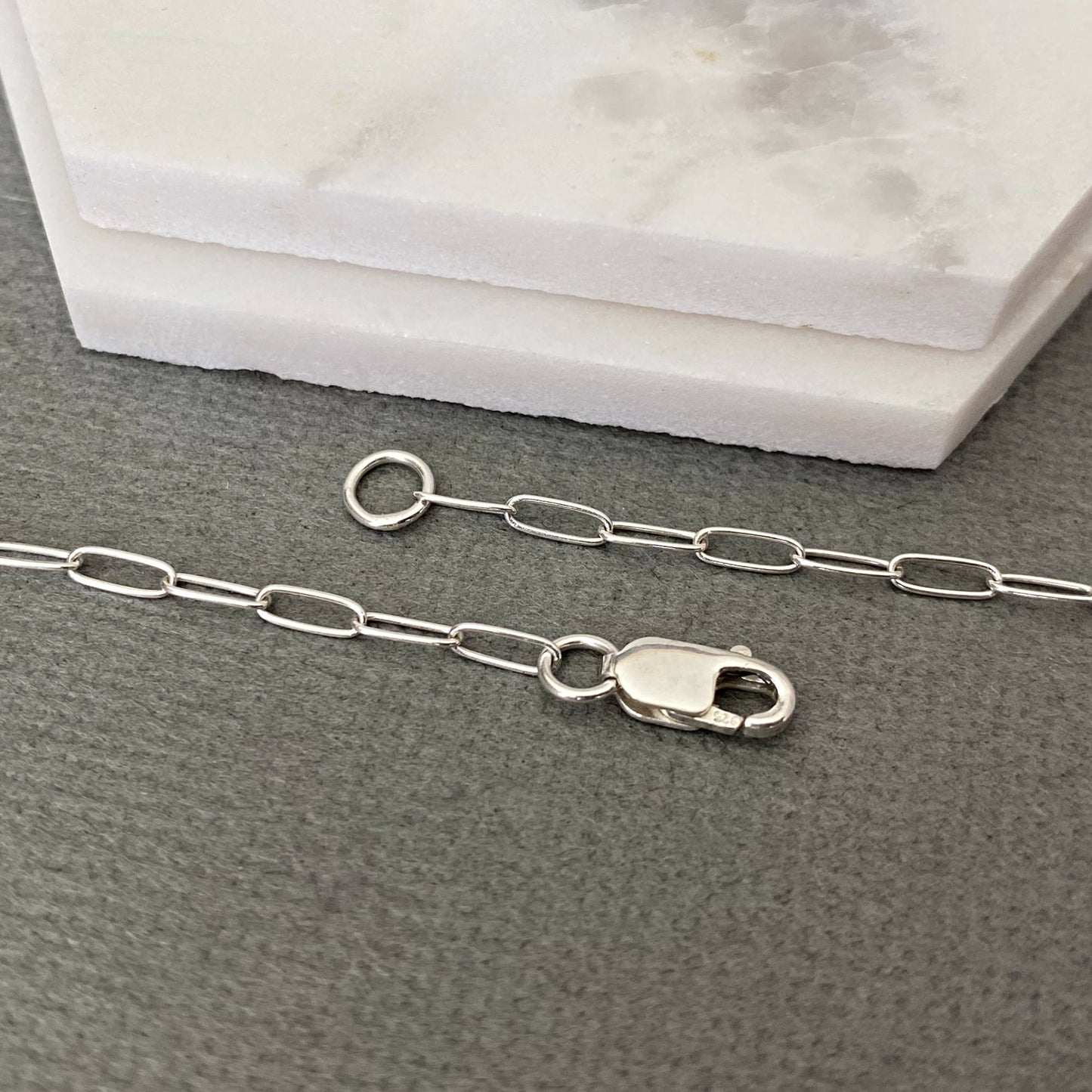 Silver chain necklace with clasp on a gray surface