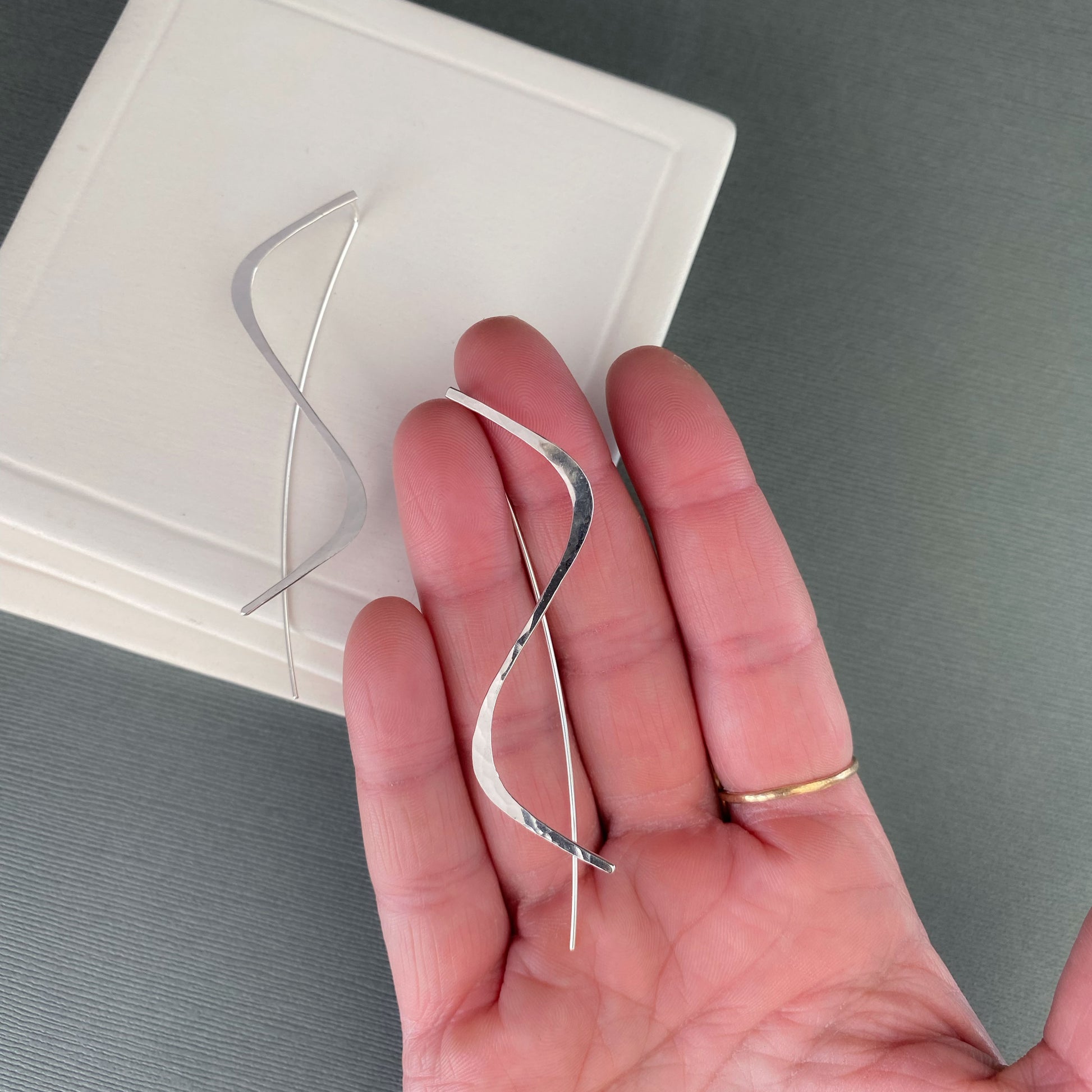 sterling silver handmade threader earrings being held in a hand.