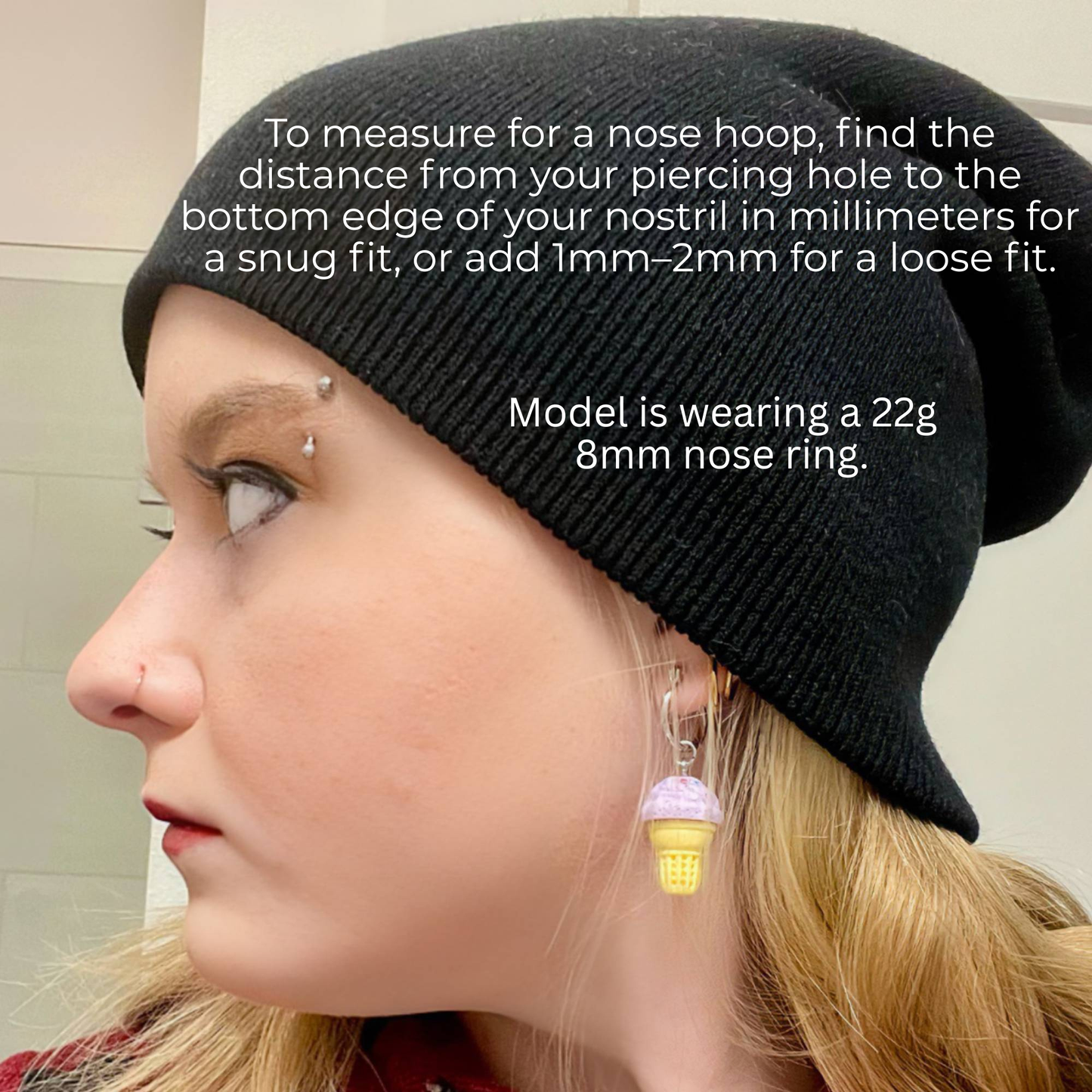 Person wearing a black beanie with text on measuring nose rings.