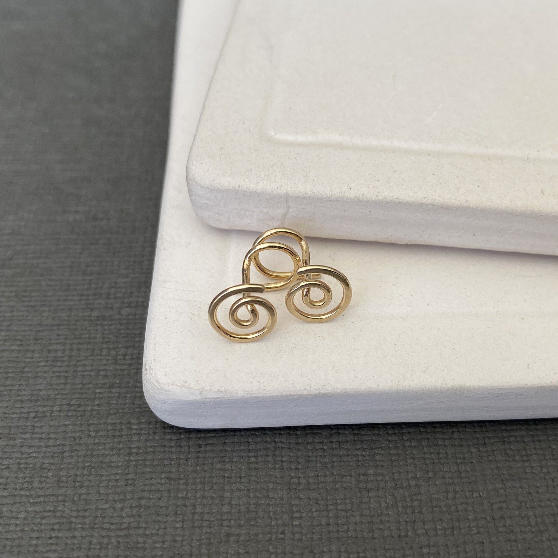 Gold spiral earring on a white jewelry display