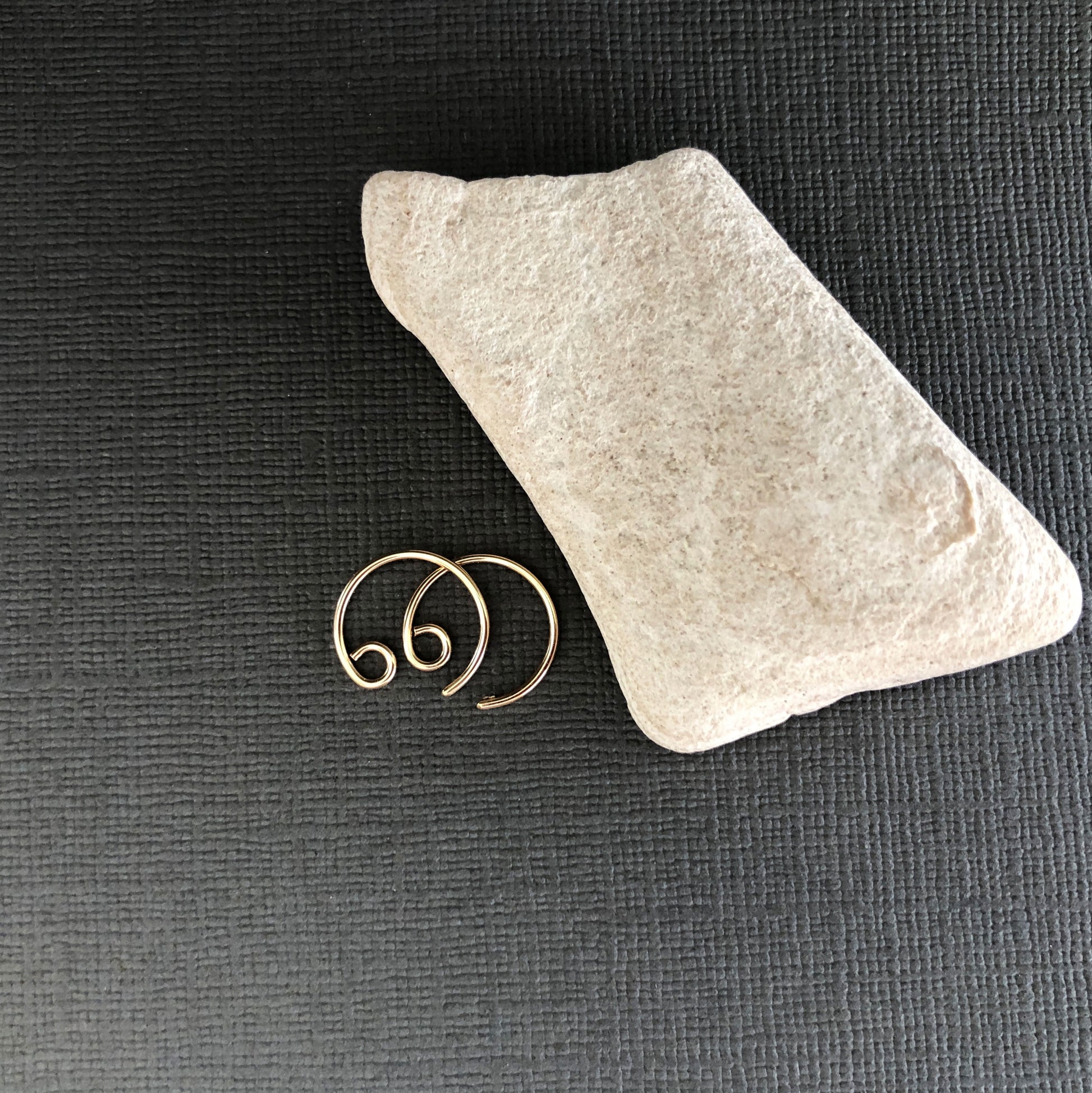 Flat lay of minimalist 14k gold filled tiny hoop earrings