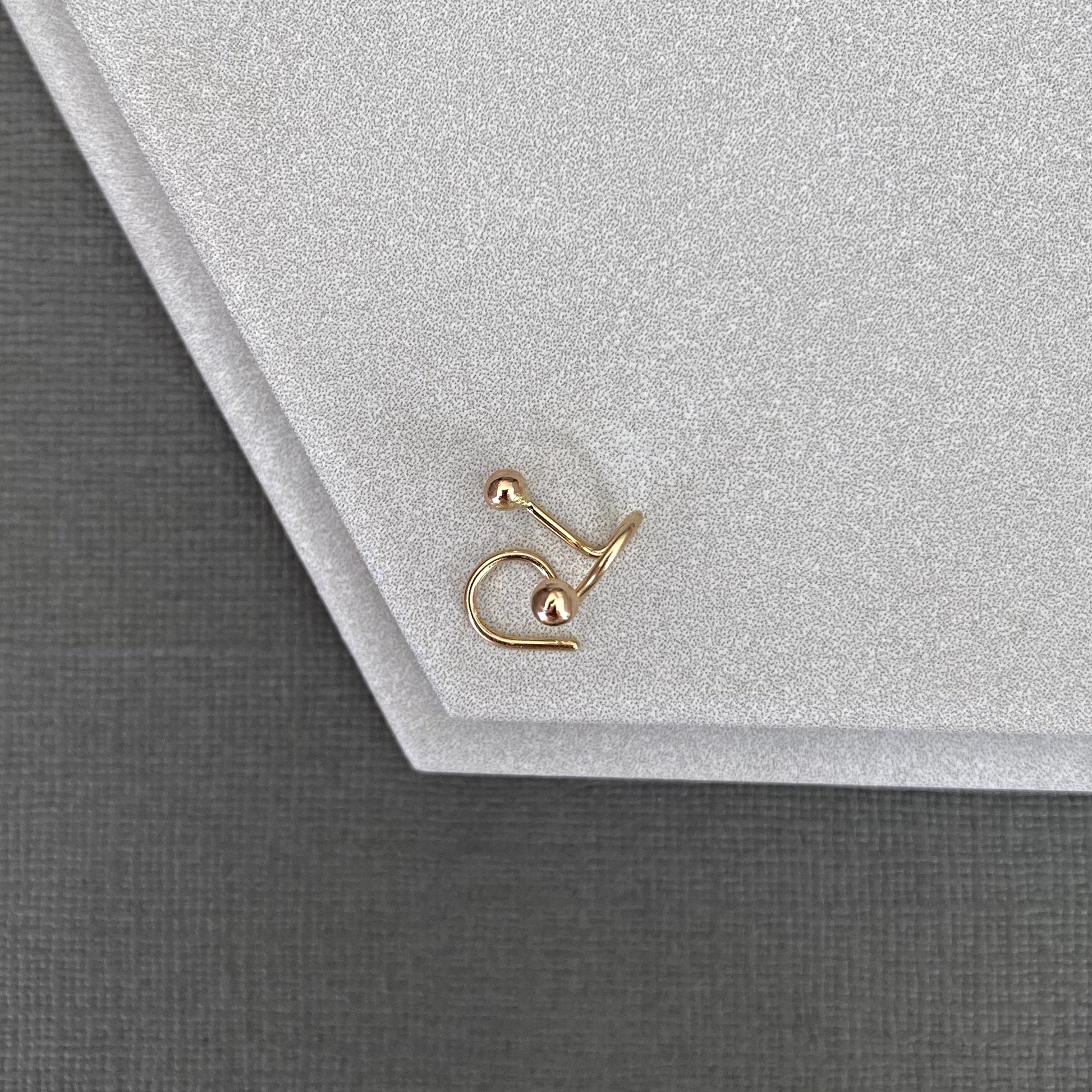 Gold earring on a textured gray surface