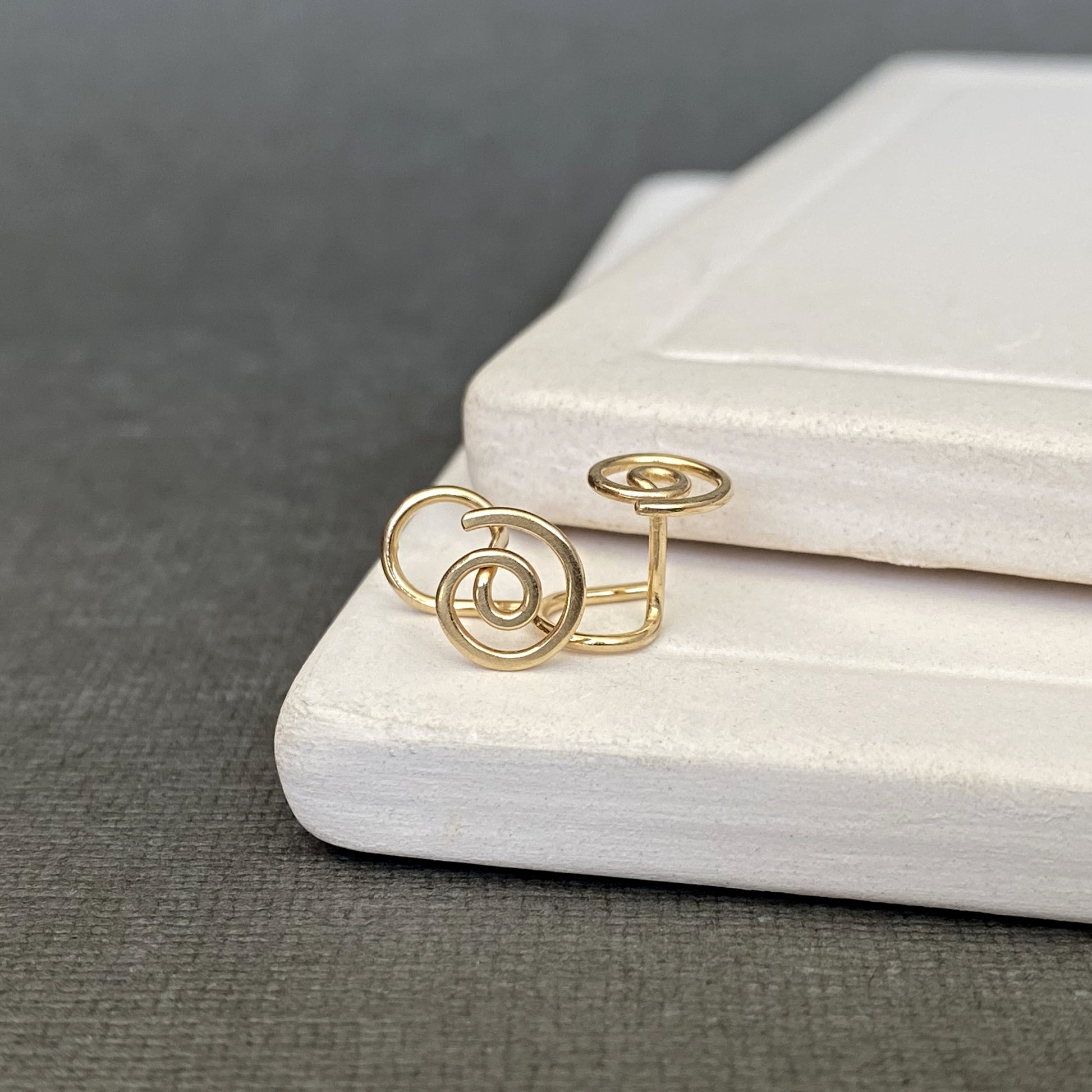 Gold spiral ring on a white stone surface with a gray background