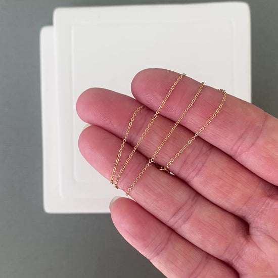 A video showing a dainty 14k gold filled chain swaying and moving. The footage highlights the fluid movement of the soldered links and the beautiful shine of the 18k gold plating.
