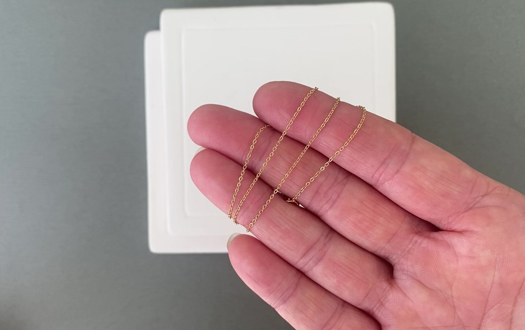 A video showing a dainty 14k gold filled chain swaying and moving. The footage highlights the fluid movement of the soldered links and the beautiful shine of the 18k gold plating.
