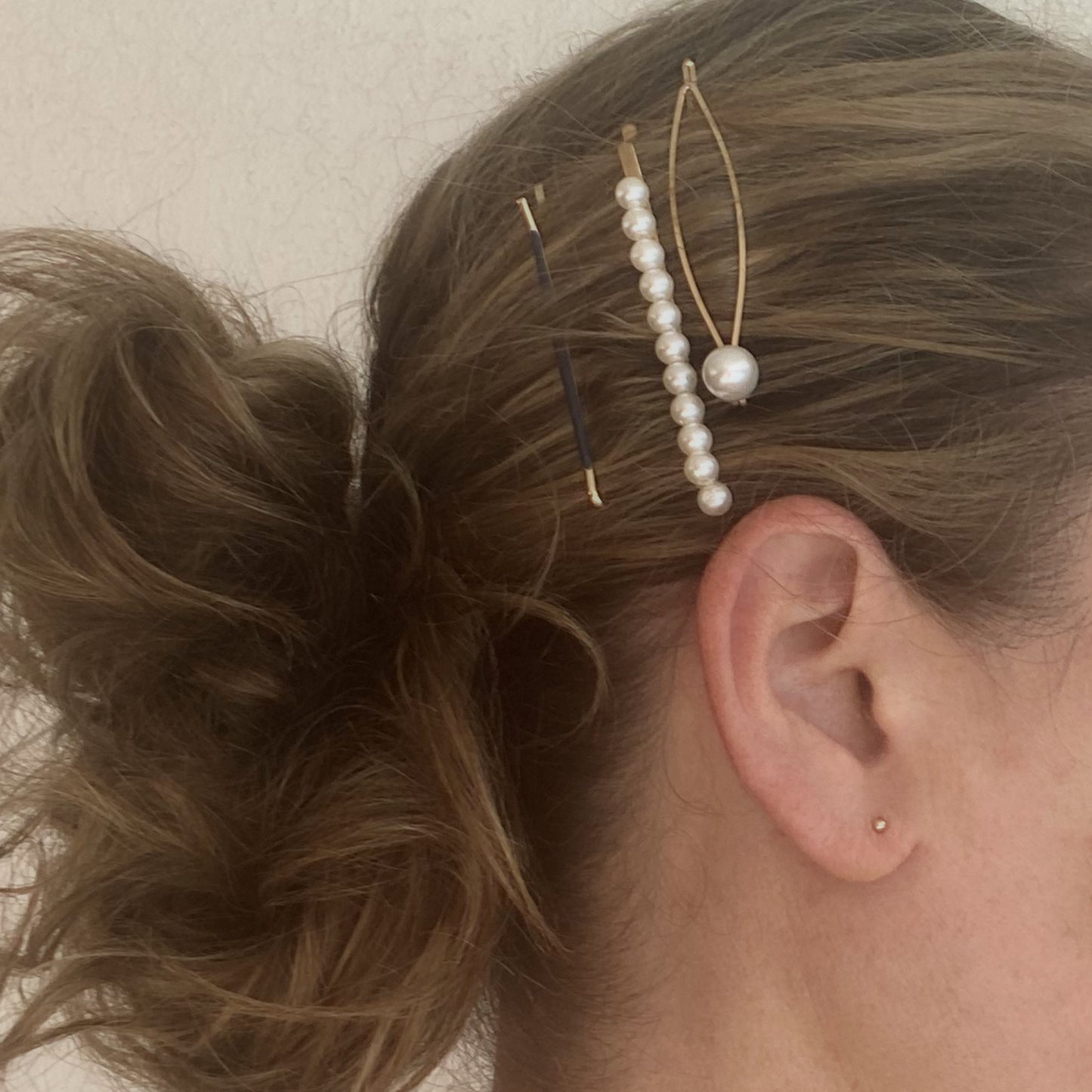 Close-up of a person's hair with decorative hairpins and earrings.
