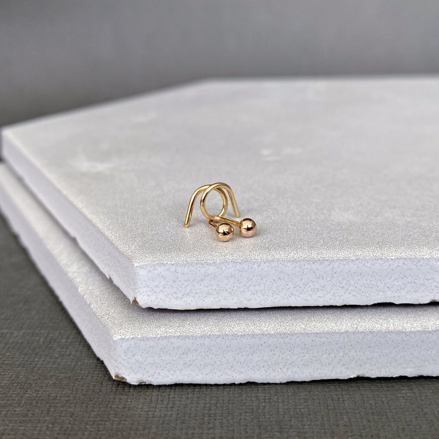 Gold ball end earring stud on a gray surface