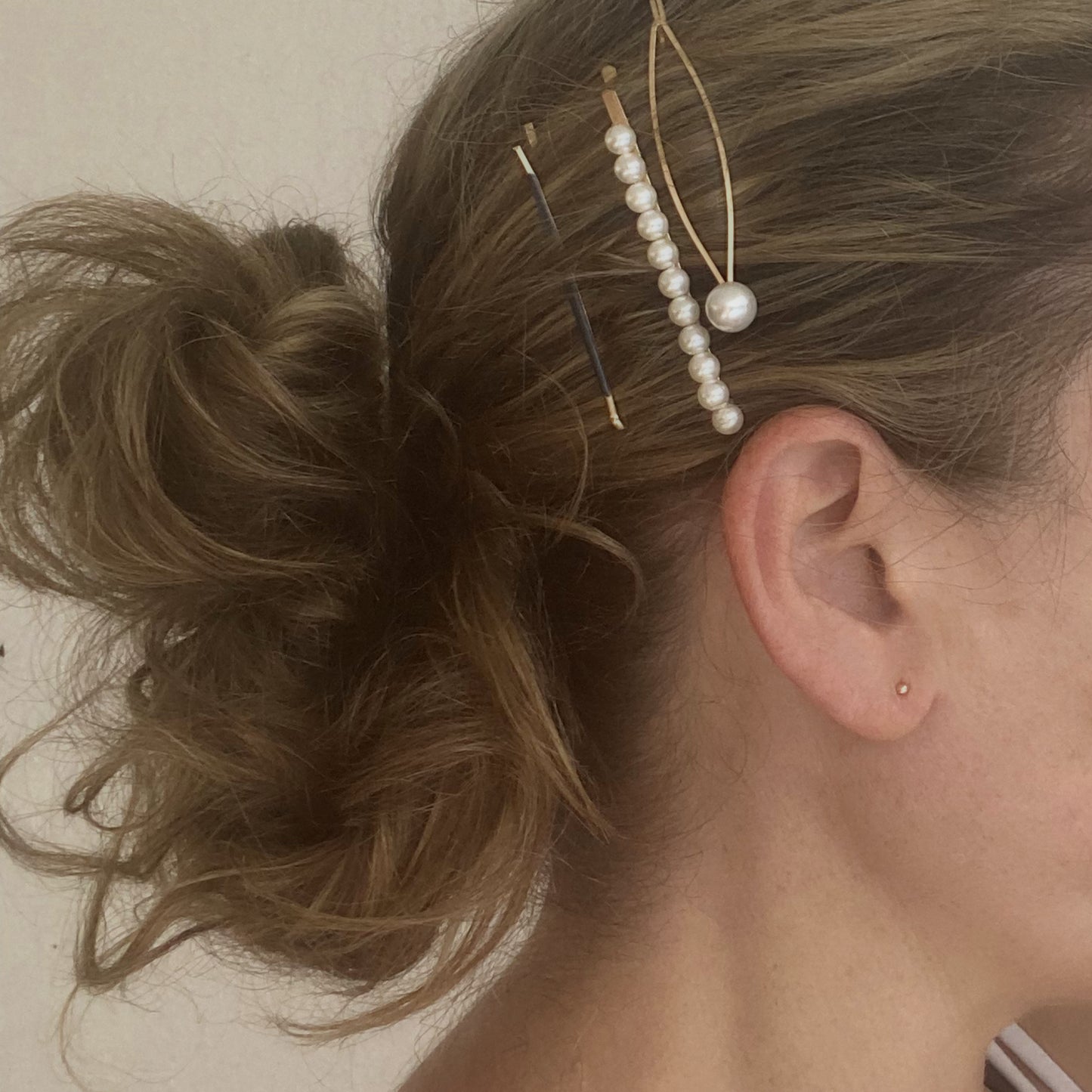 Close-up of a person's hair with decorative hairpins and earrings.